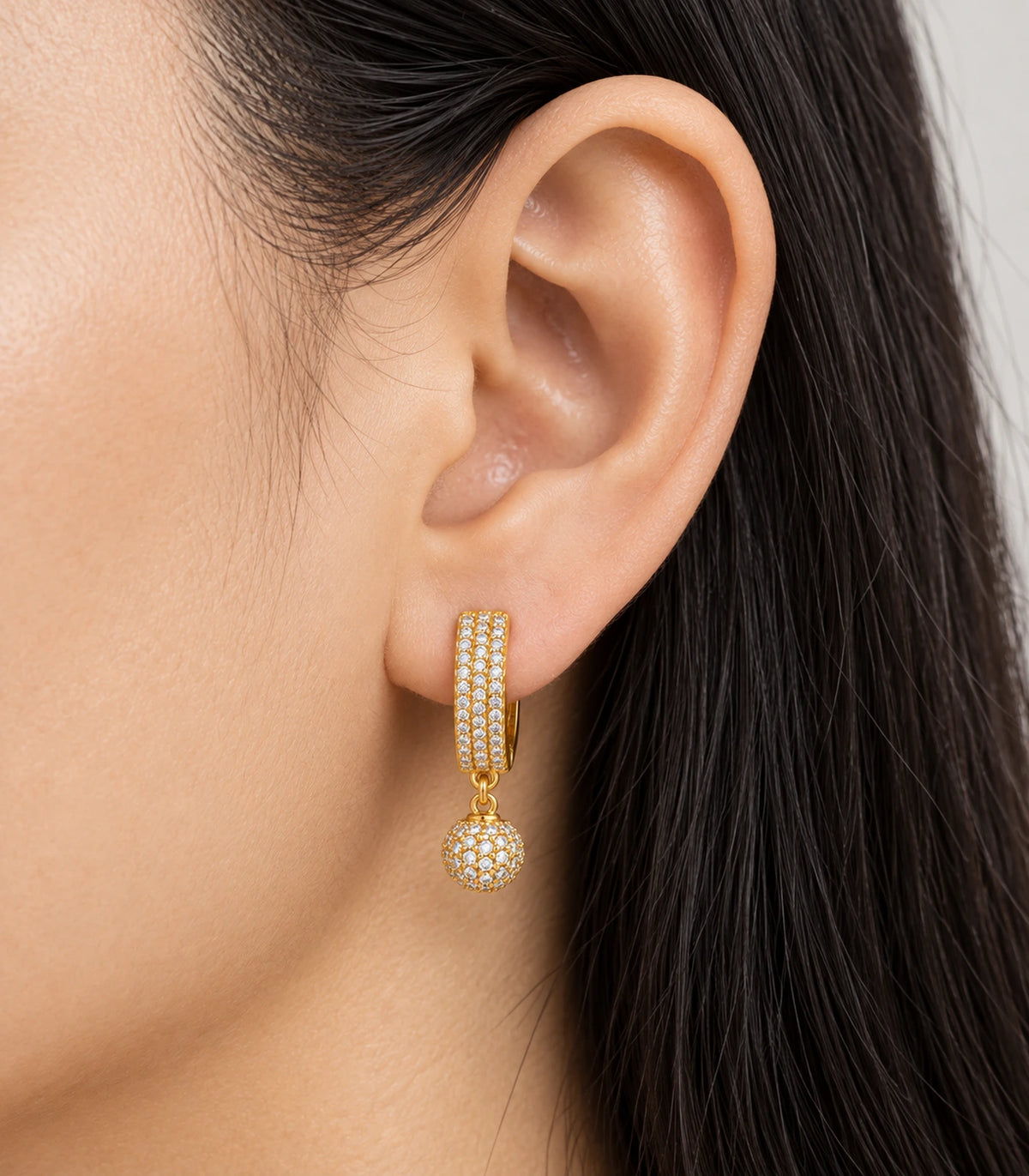 JIMIKI Gold-Tone Three-Row Pavé Ball Drop Huggie Earrings — close-up of the earring design #color_gold-tone / clear