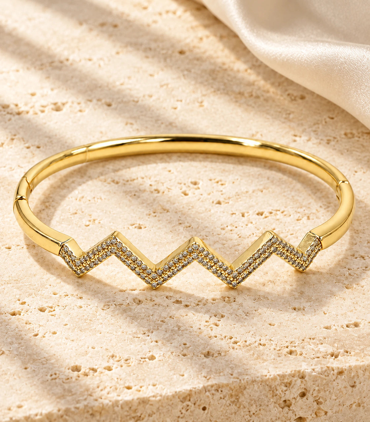 JIMIKI Gold-Tone Triple Chevron Pavé Bangle — bangle in a styled flat lay #color_gold-tone / clear