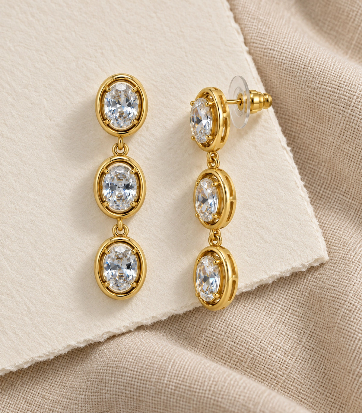 JIMIKI Triple Oval Crystal Drop Earring Pair in Gold tone, editorial flat lay #color_gold tone
