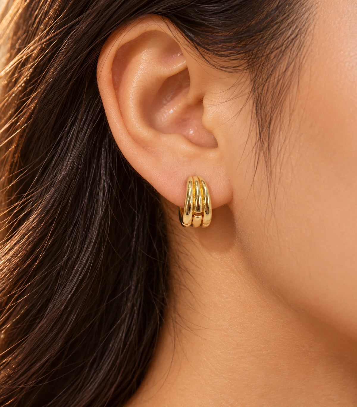 JIMIKI Triple-Ridge Huggie Hoop Earrings in Gold Tone - editorial-model #color_gold-tone