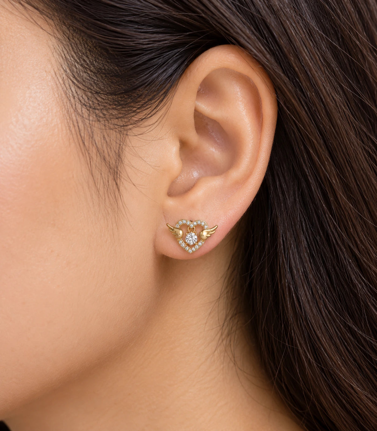 JIMIKI Winged Heart Crystal Stud Earrings in Gold Tone — worn styling view #color_gold-tone
