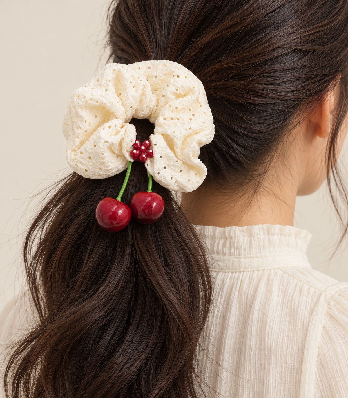 Ivory eyelet cherry scrunchie with dotted red flower centre — model view