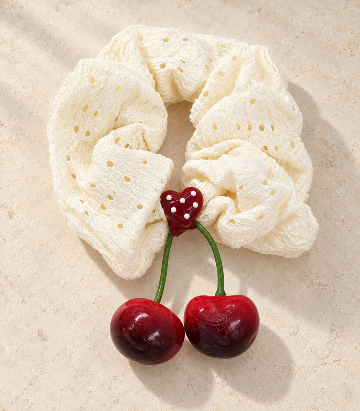 Ivory eyelet cherry scrunchie with dotted heart centre — editorial flatlay view
