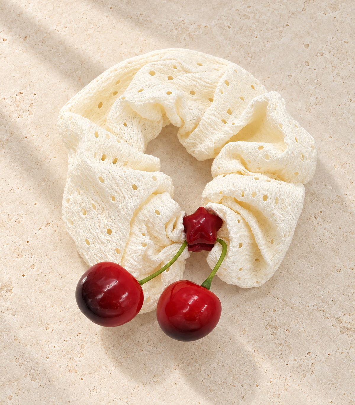 Ivory eyelet cherry scrunchie with red star centre — editorial flatlay