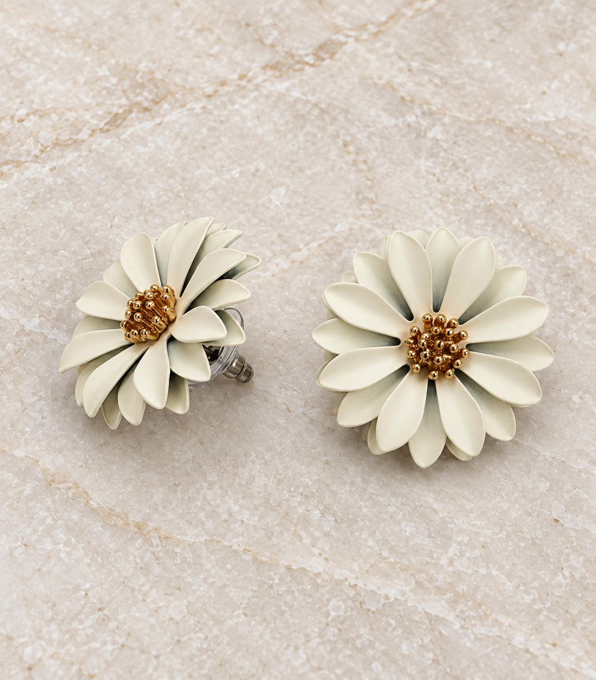 JIMIKI Ivory layered starburst daisy stud earrings, matching pair in a styled flat lay #color_ivory