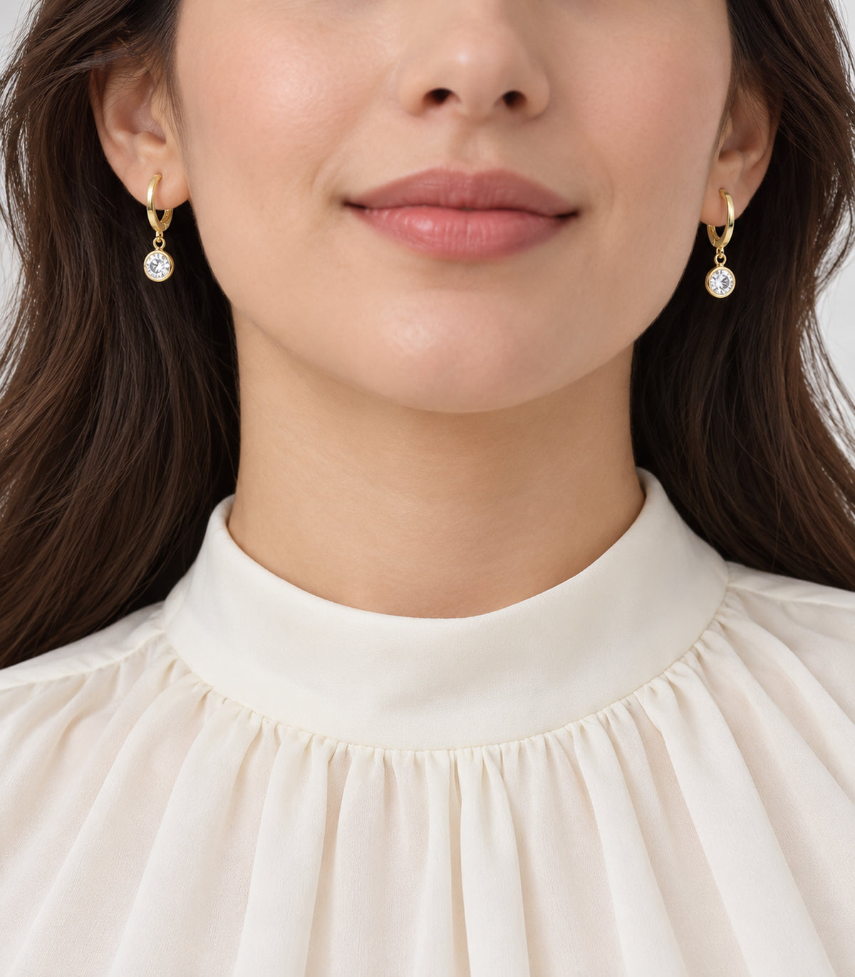 Clear round crystal drop hoops from the gold tone three-pair set, styled with an ivory high-neck garment.