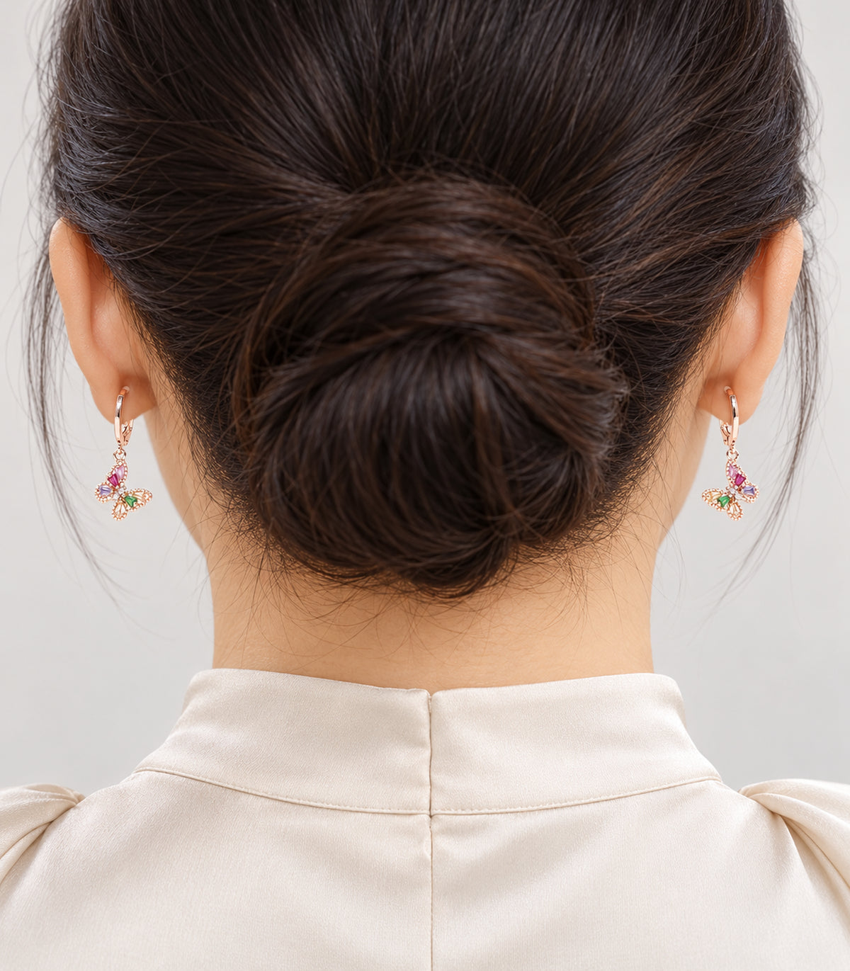 Rose gold tone hoop earrings worn to show a design from the three-pair set