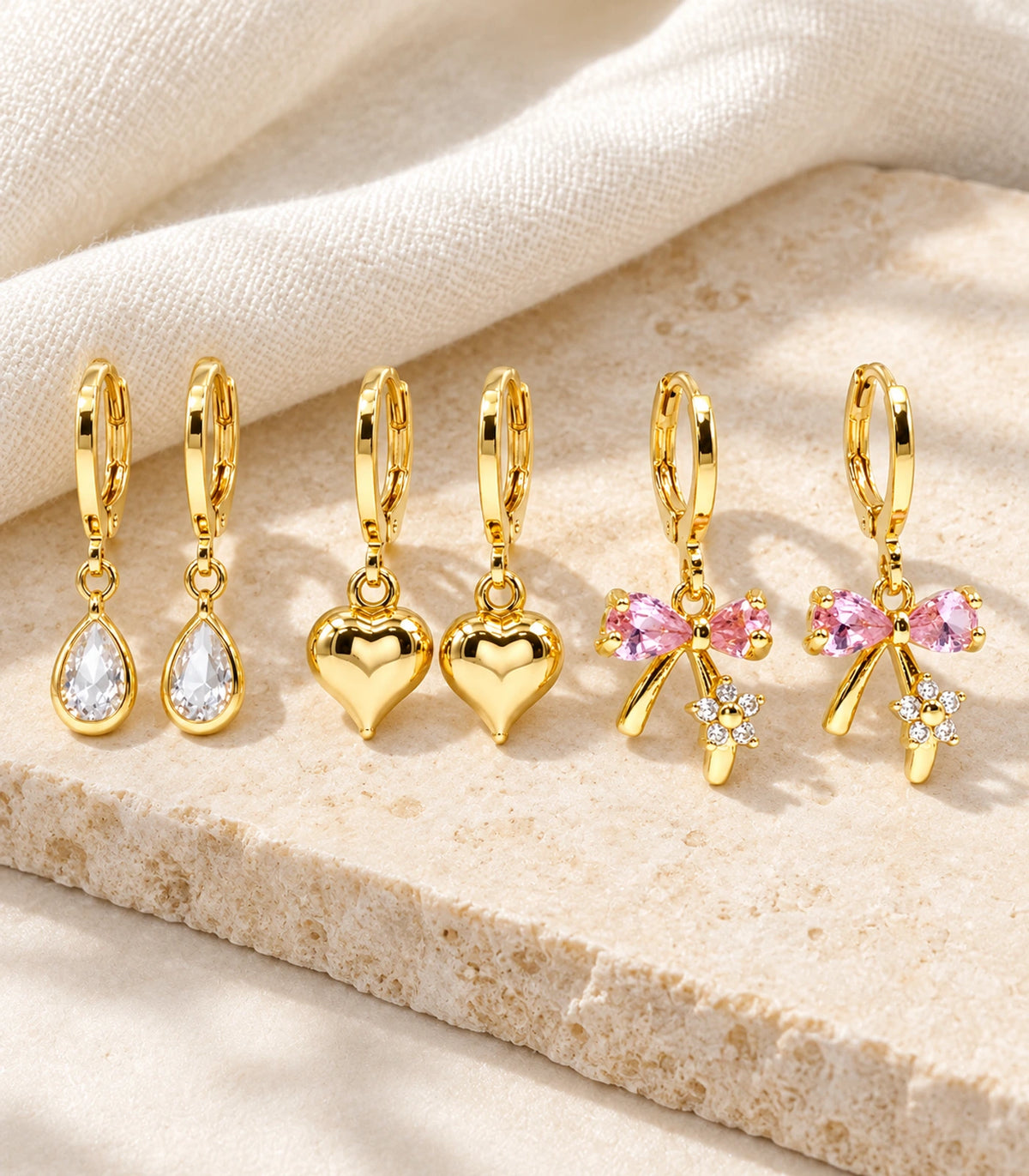 Complete six-earring gold-tone teardrop, heart and pink bow set in editorial flatlay