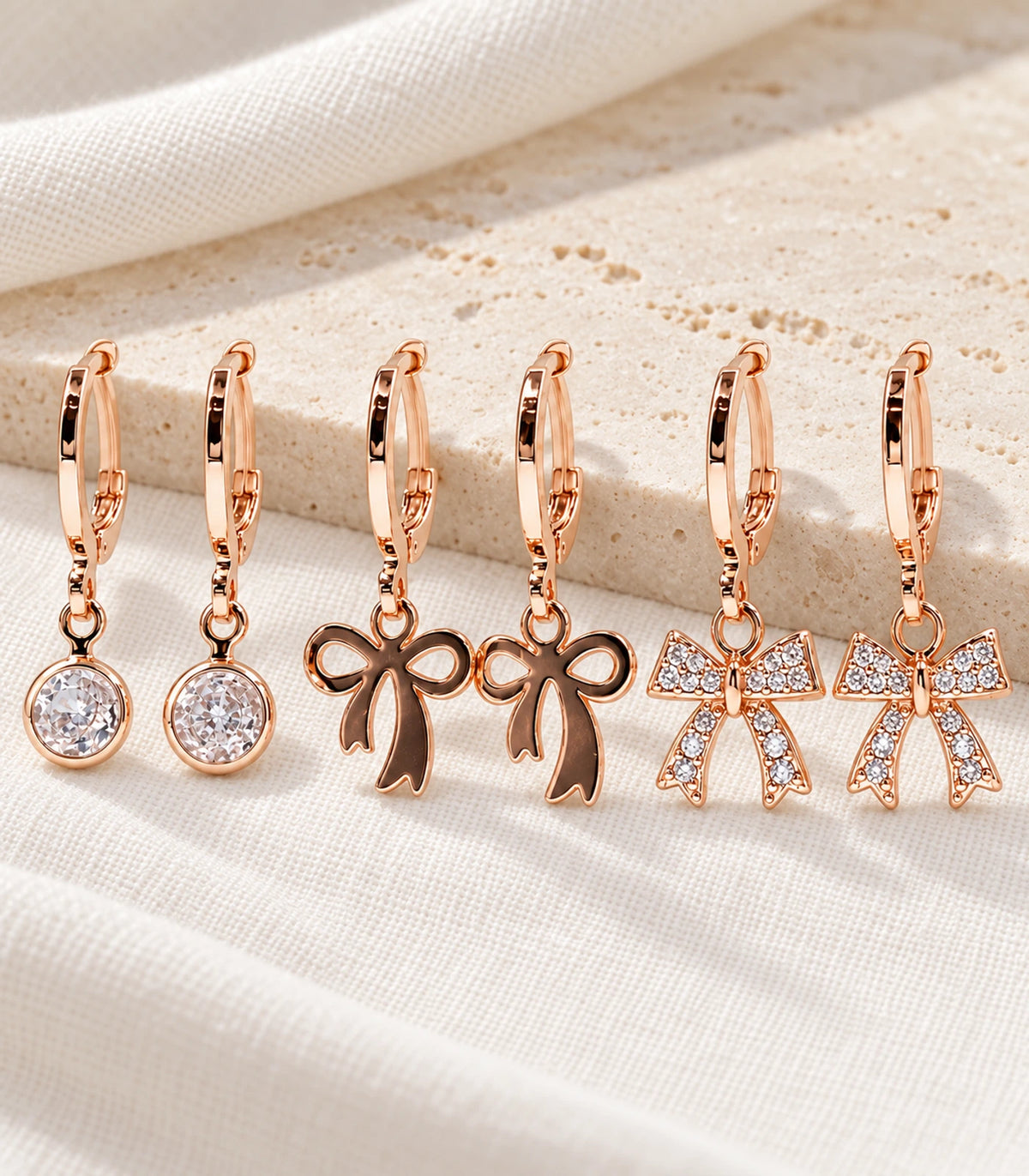 Complete six-earring rose gold tone assortment arranged on ivory fabric and pale stone