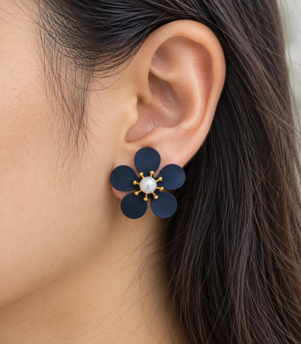JIMIKI navy five-petal flower stud earrings with pearl-effect centre, closeup of flower stud in a natural worn setting #color_navy