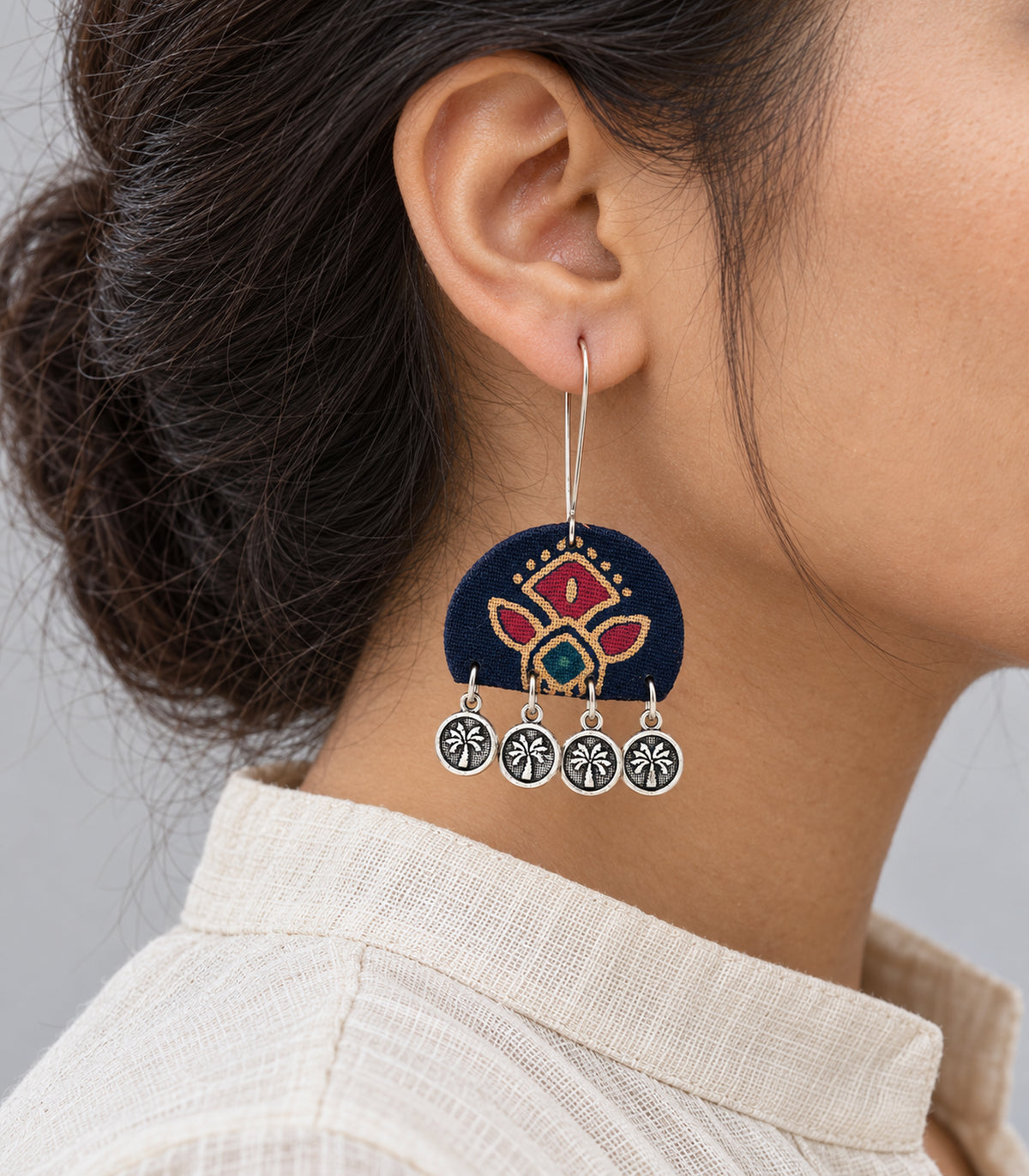 Closeup of a worn navy floral fabric earring and its four coin drops