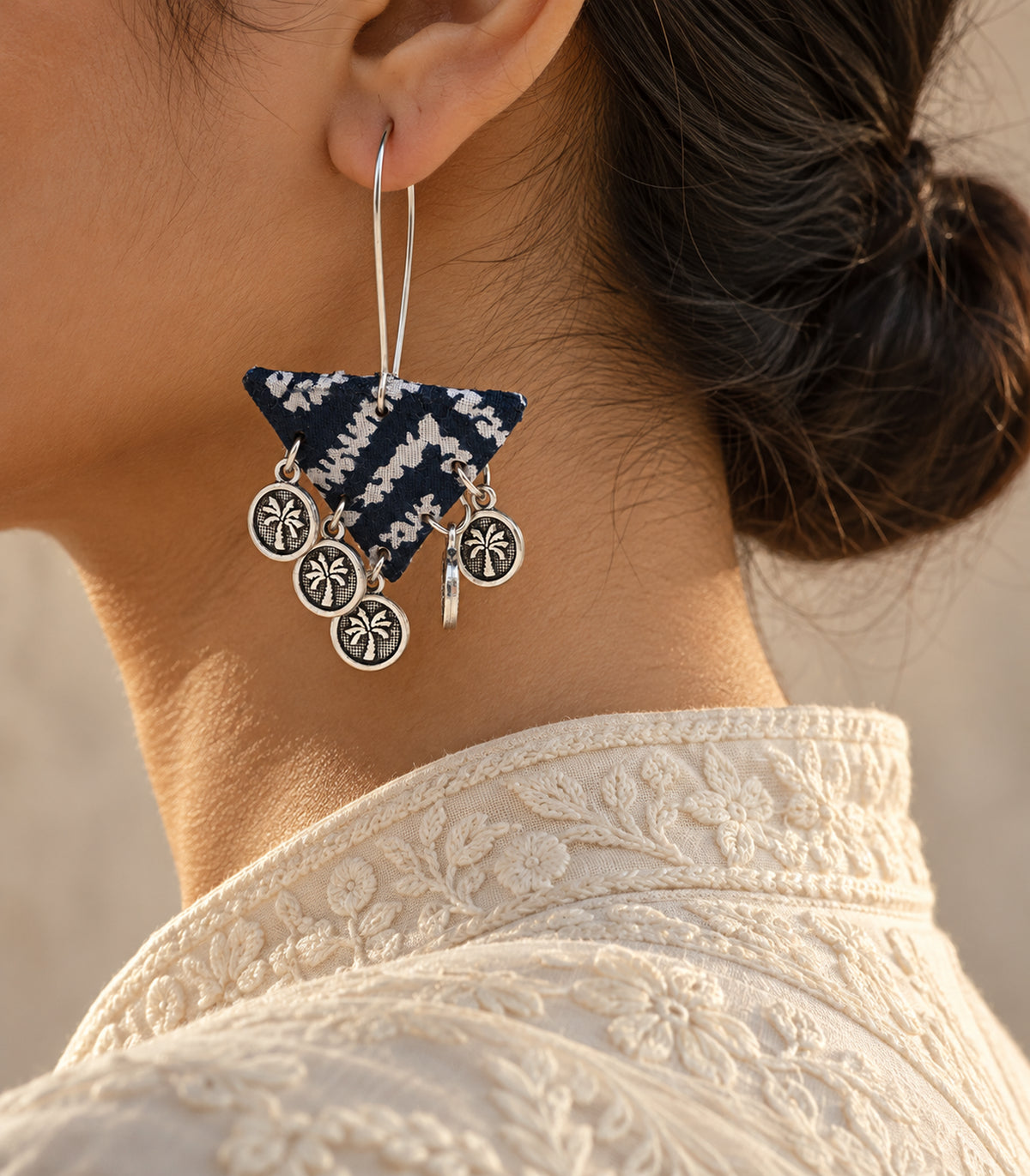 Navy and white triangle coin earring worn with an ivory collar
