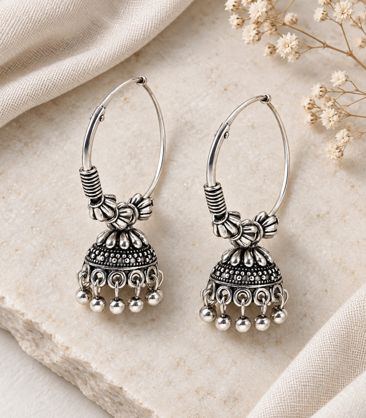 JIMIKI Oxidized Silver Floral Hoop Jhumka Earrings - styled pair with textured fabric #color_oxidized-silver