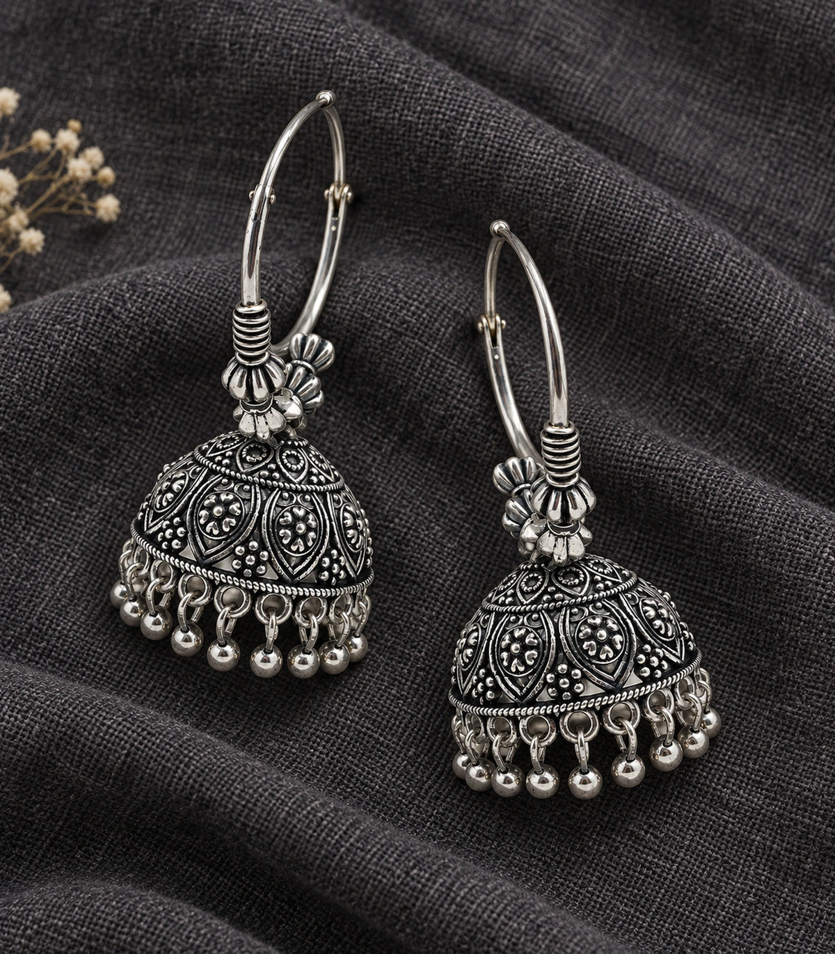 JIMIKI Oxidized Silver Floral Paisley Hoop Jhumka Earrings - styled pair with textured fabric #color_oxidized-silver