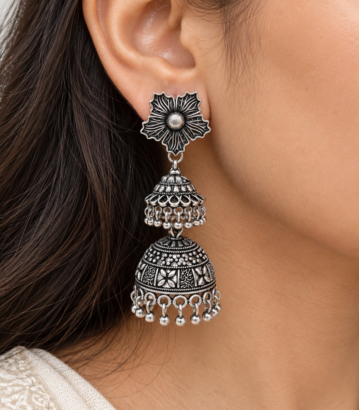 JIMIKI Oxidized Silver Hibiscus Double Jhumka Earrings - close-up of floral stud and patterned bell #color_oxidized-silver