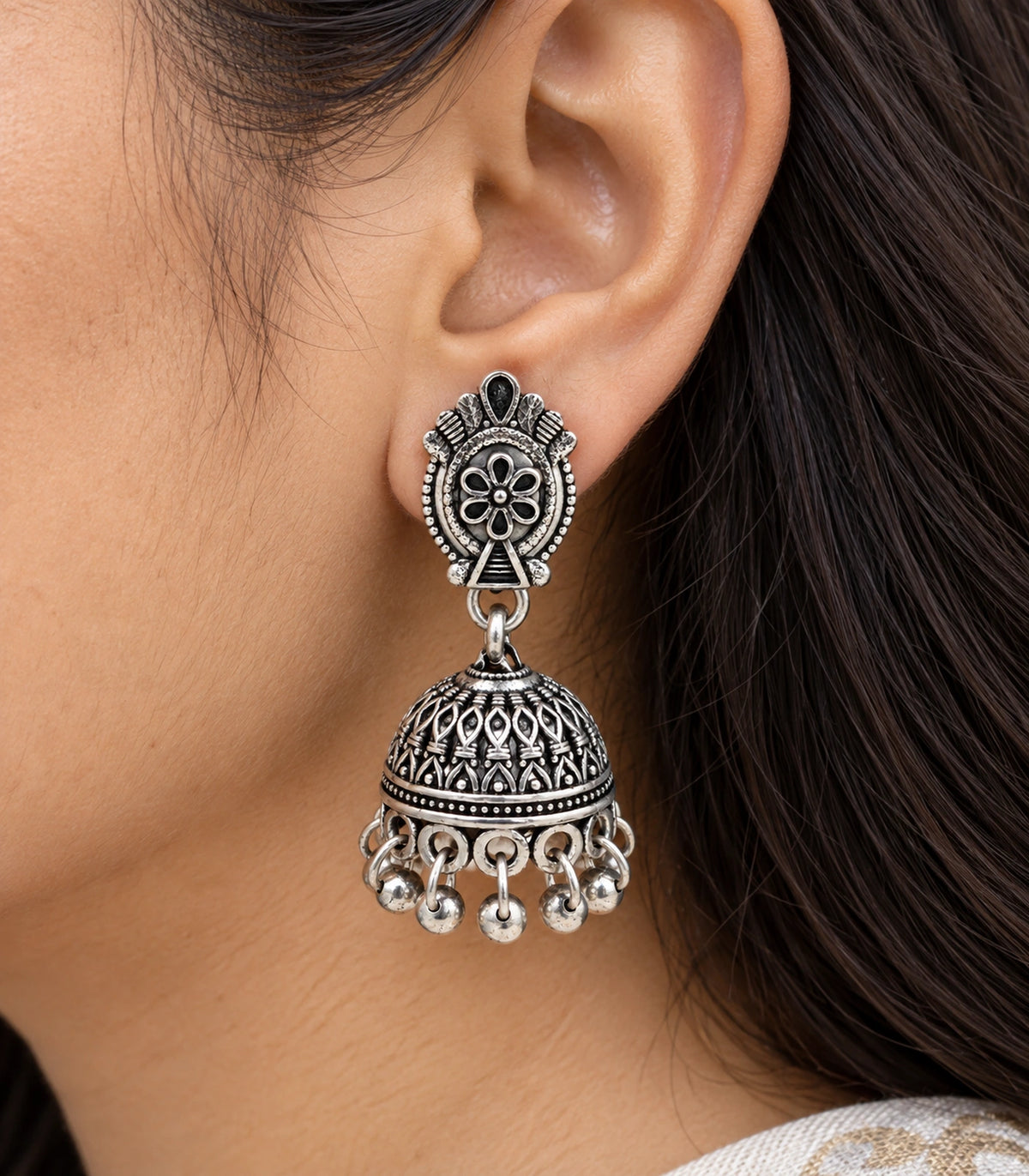 JIMIKI Oxidized Silver Oval Floral Jhumka Earrings - Worn close-up of oval floral stud and patterned bell #color_oxidized-silver