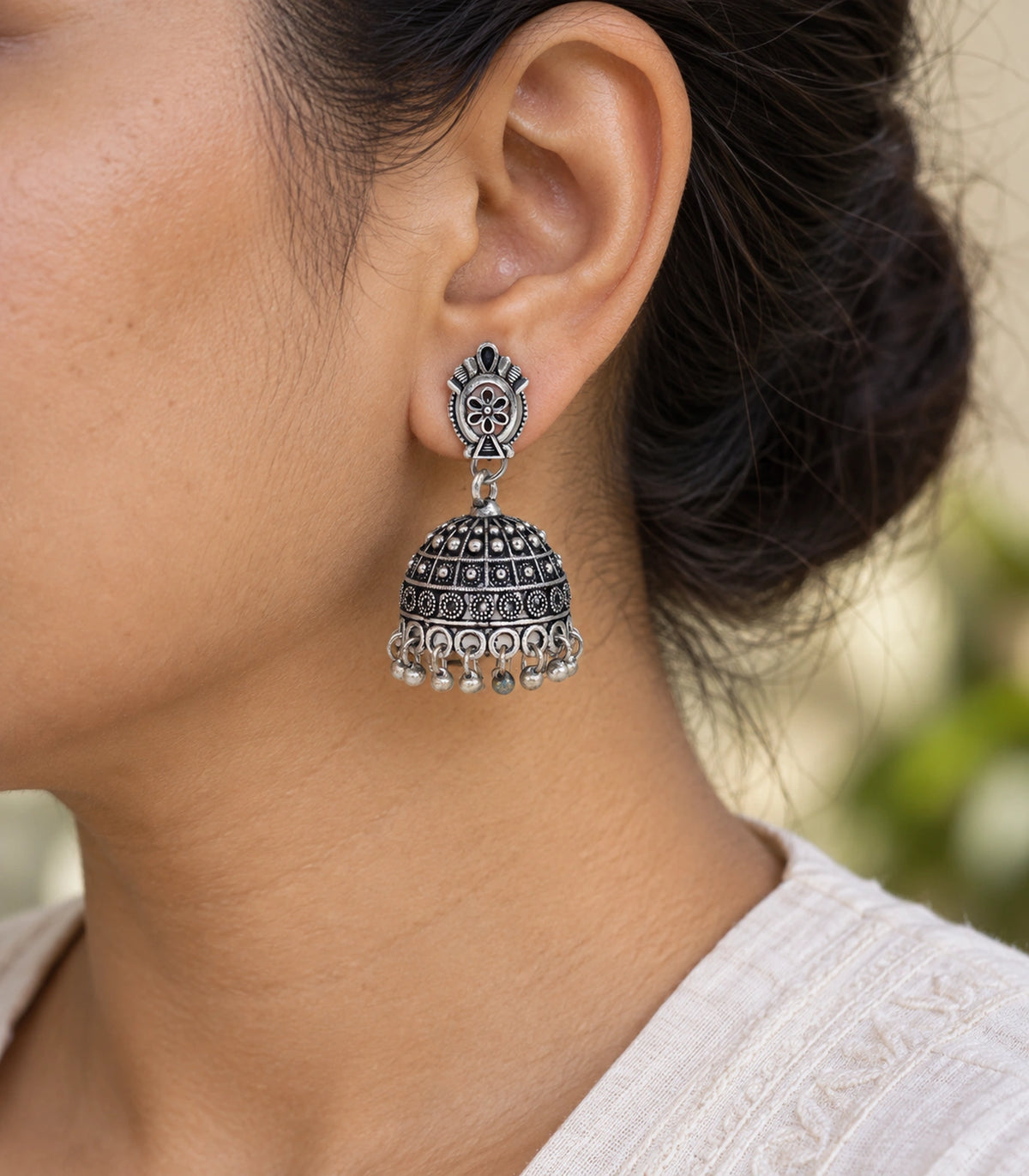 JIMIKI Oxidized Silver Oval Flower Grid Dome Jhumka Earrings - earring worn with a clear view of the design #color_oxidized-silver