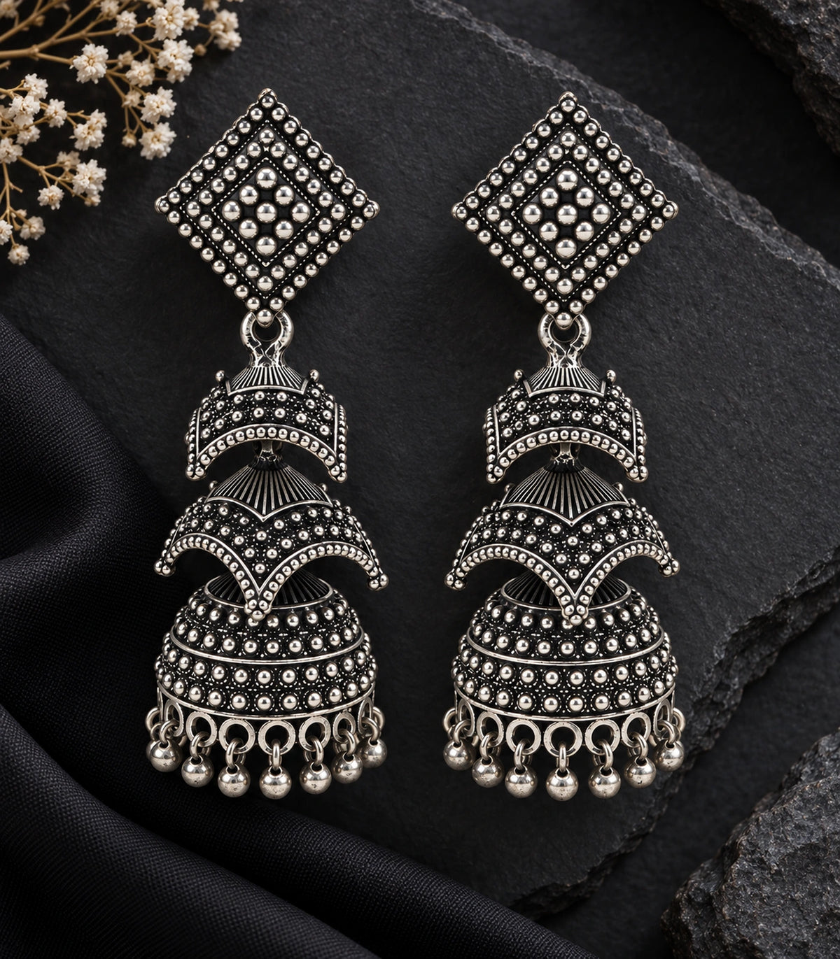 JIMIKI Oxidized Silver Tiered Chevron Jhumka Earrings - styled jewellery flat lay #color_oxidized-silver