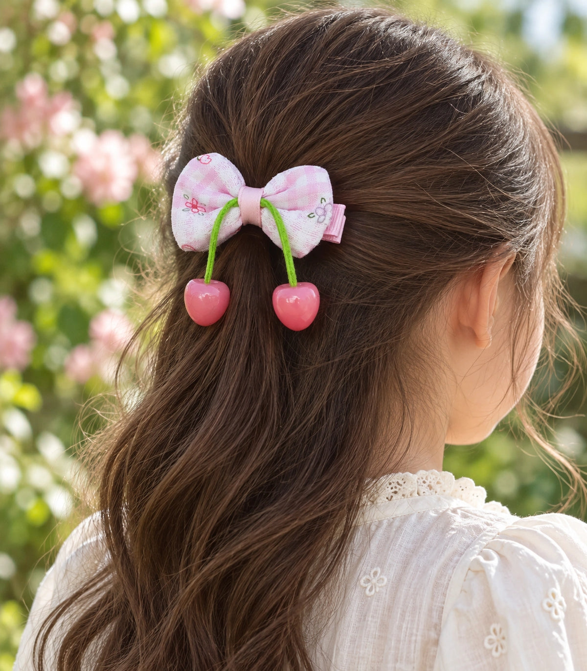 JIMIKI Pink Gingham Floral Bow Hair Clip with Cherry Charms in Pink, editorial model view