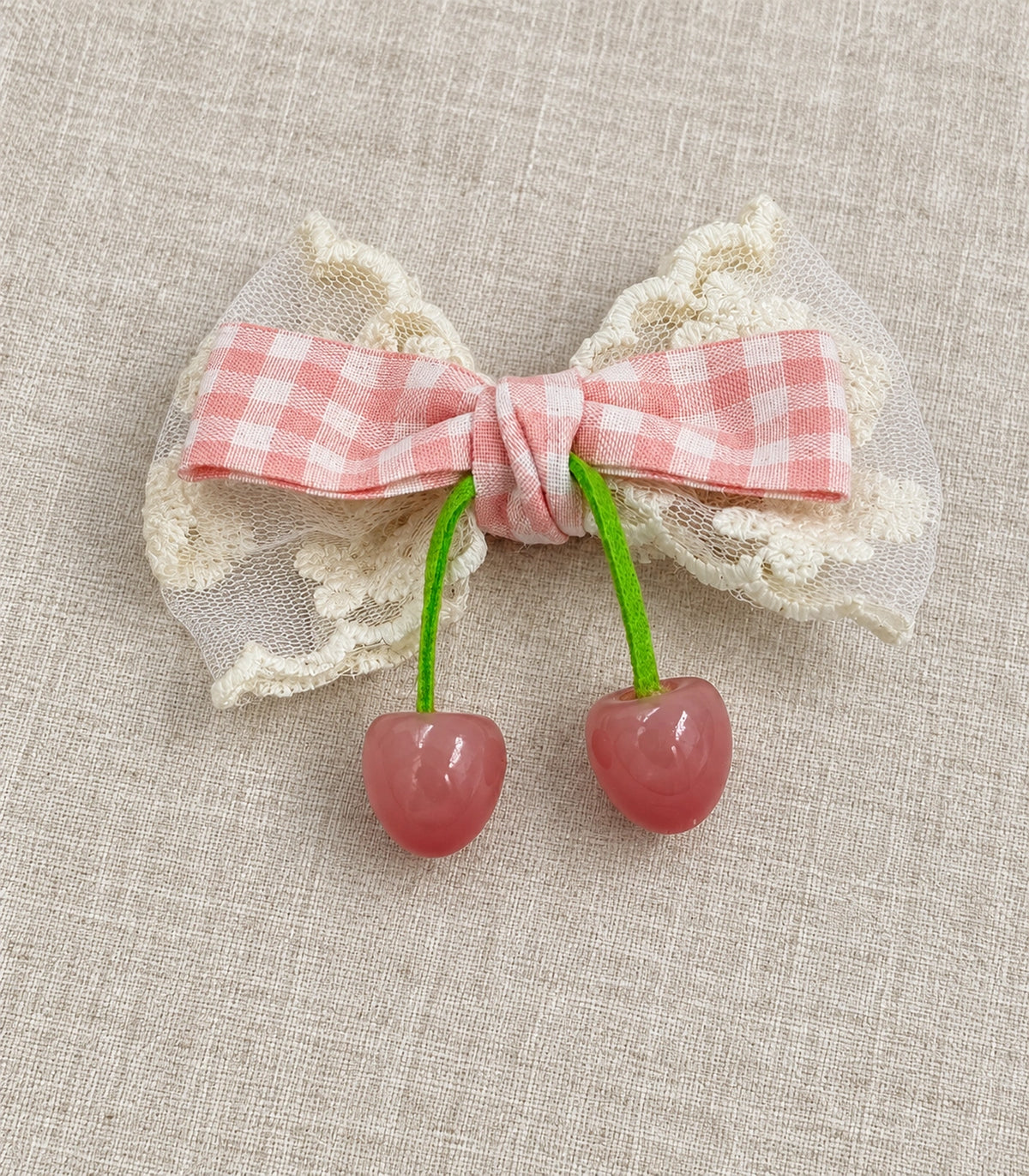 JIMIKI Pink Gingham Lace Bow Hair Clip with Cherry Charms in Pink, editorial flat lay