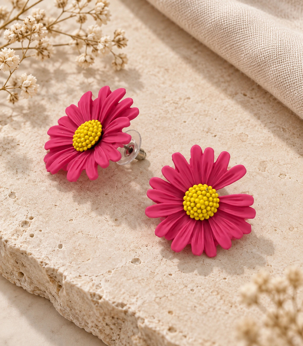 JIMIKI Pink yellow centre daisy stud earrings, matching pair on a styled stone surface #color_pink