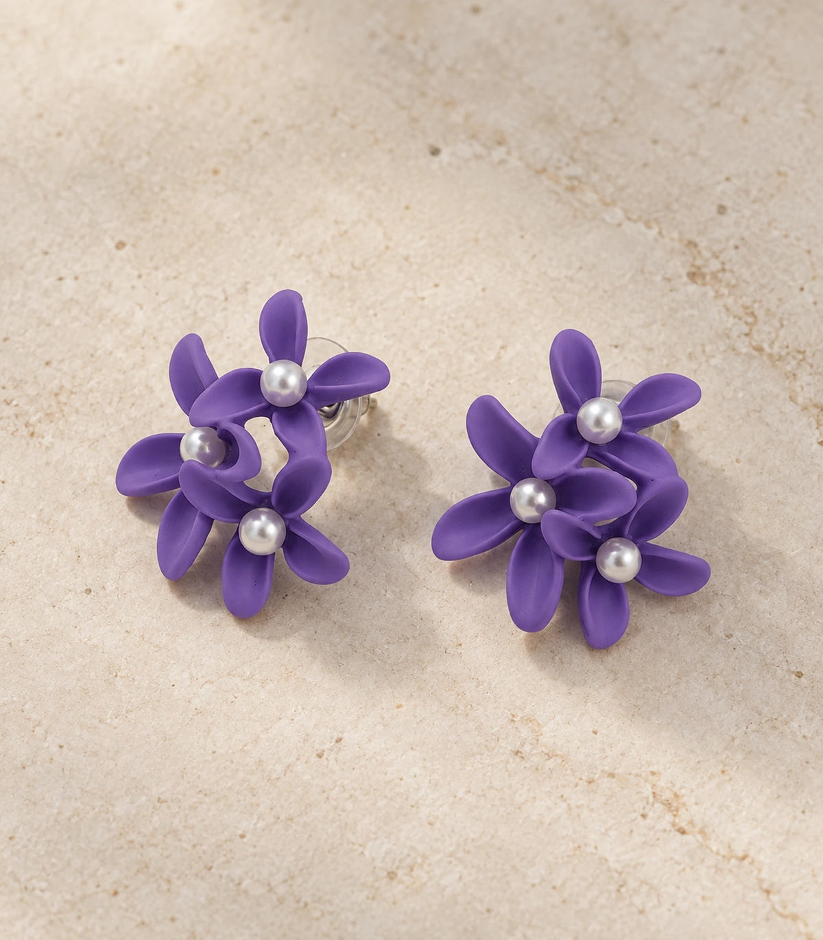 JIMIKI Purple cascading floral cluster stud earrings, matching pair styled on a light textured surface #color_purple