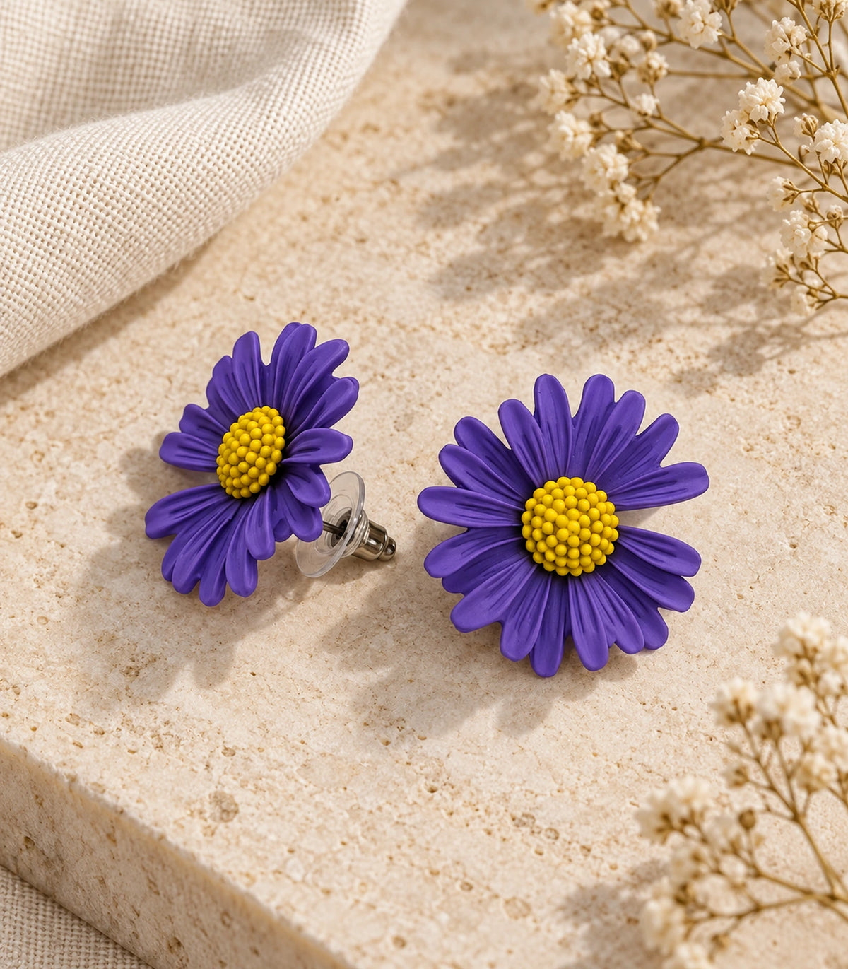 JIMIKI Purple yellow centre daisy stud earrings, matching pair on a styled stone surface #color_purple