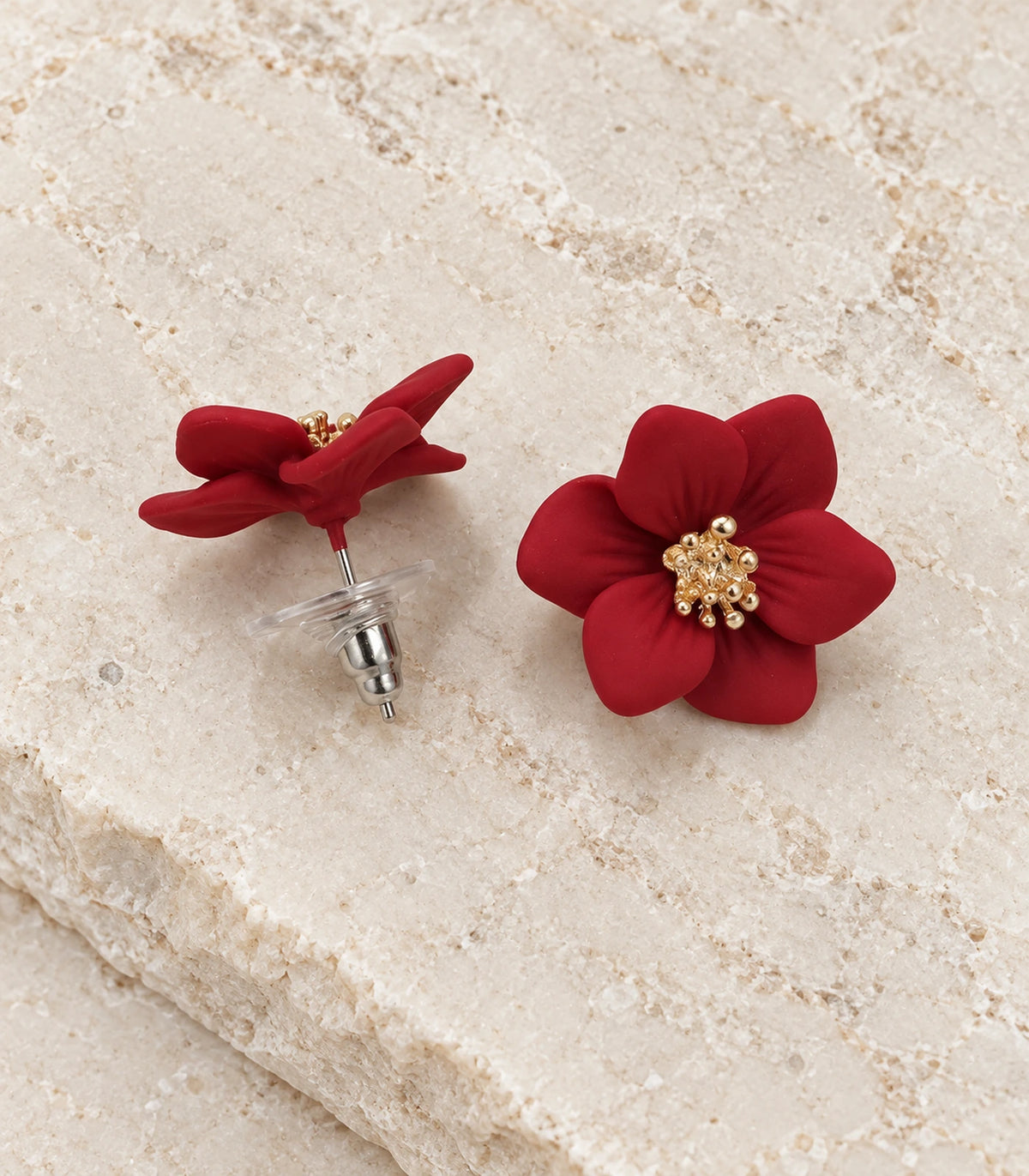 JIMIKI Red compact six petal flower stud earrings, matching pair in a styled flat lay #color_red