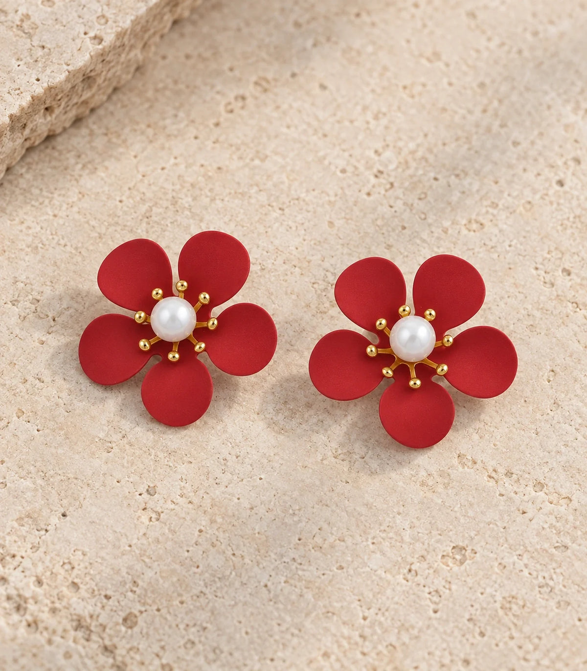 Red five-petal pearl flower stud earrings editorial flat lay