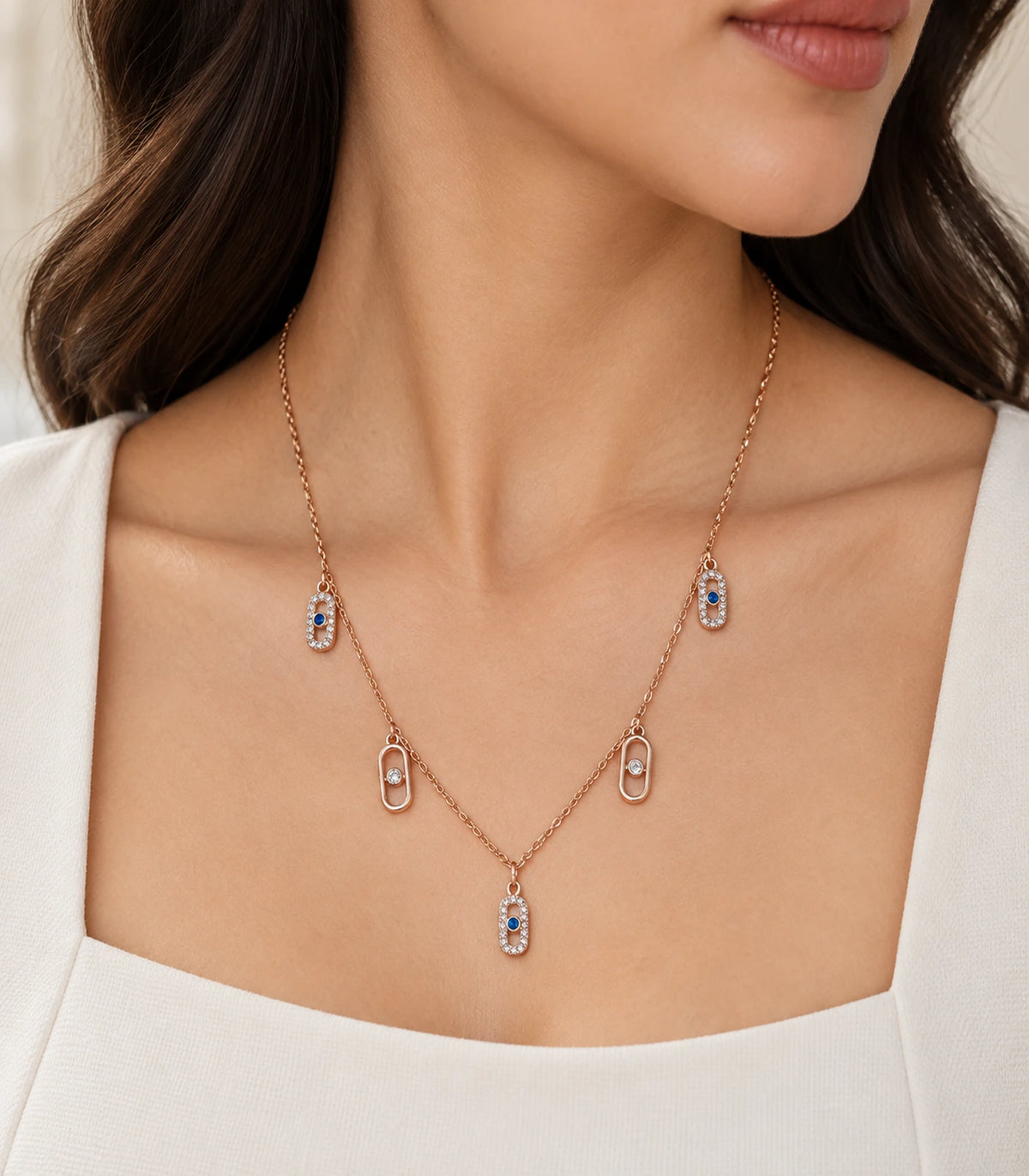 JIMIKI Rose Gold Blue Clear Oval Station Necklace - oval station necklace in an editorial worn view #color_rose-gold