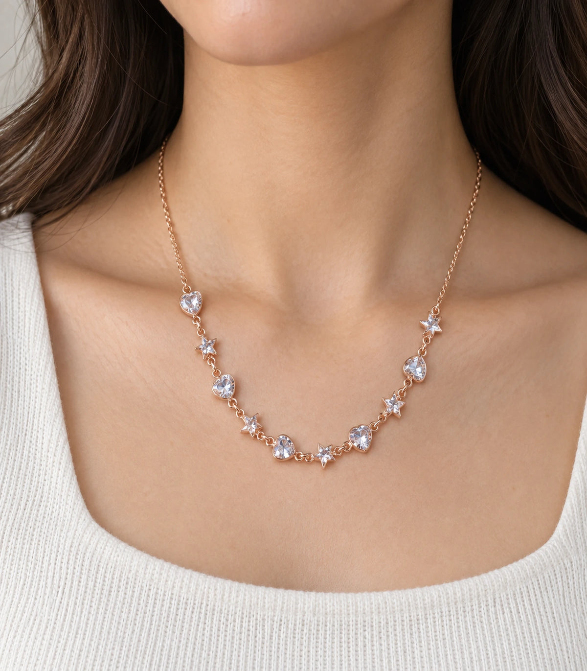 JIMIKI Rose Gold Crystal Heart Star Station Necklace - worn closeup of alternating heart and star stations #color_rose-gold
