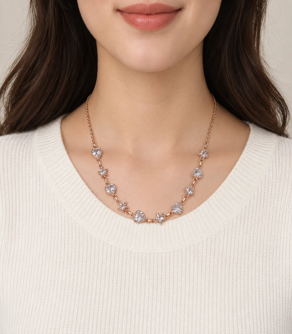 JIMIKI Rose Gold Crystal Heart Star Station Necklace - heart and star necklace worn with an ivory knit #color_rose-gold