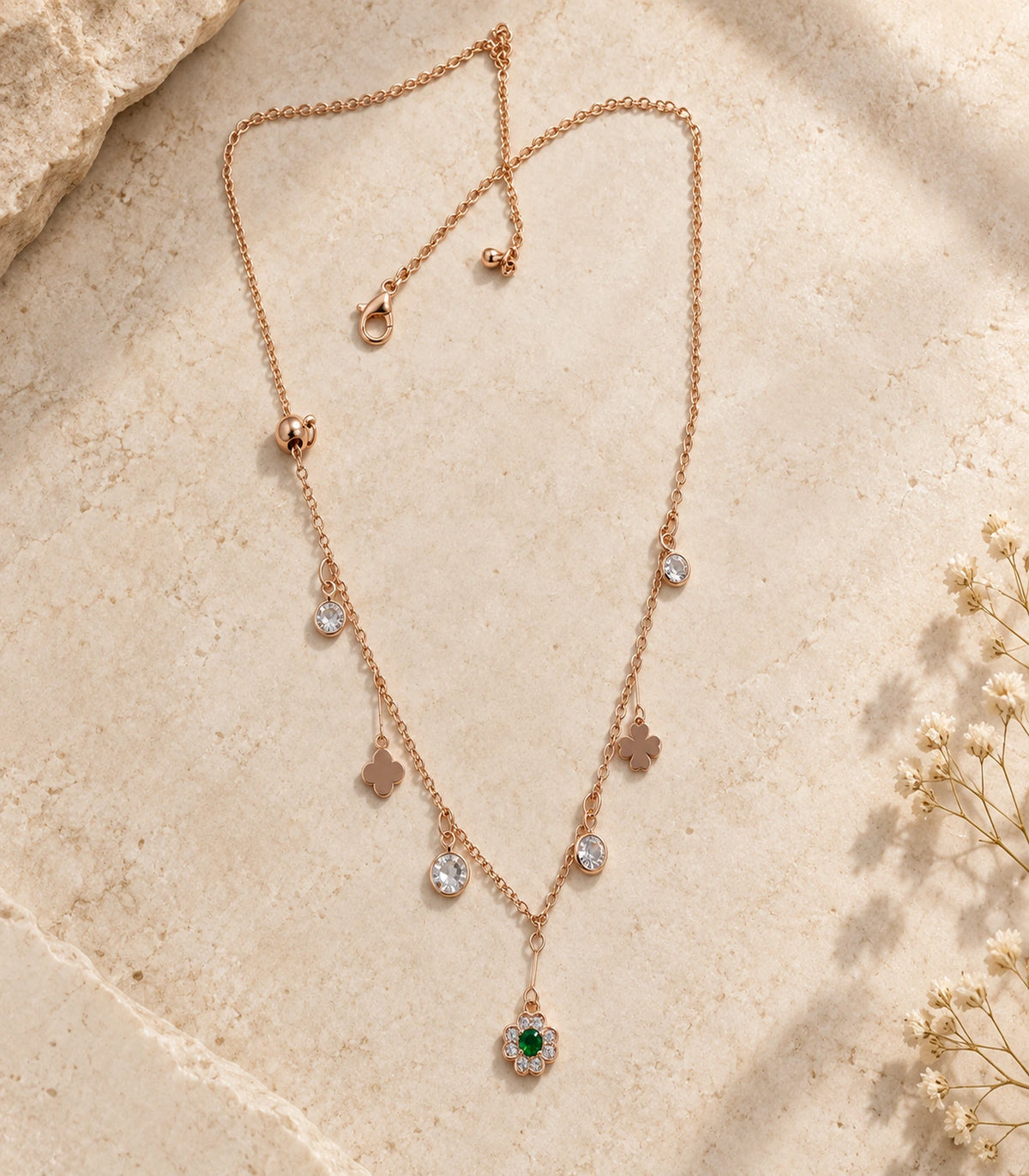 JIMIKI Rose Gold green flower and clover charm necklace, complete necklace arranged on a pale textured surface #color_rose gold
