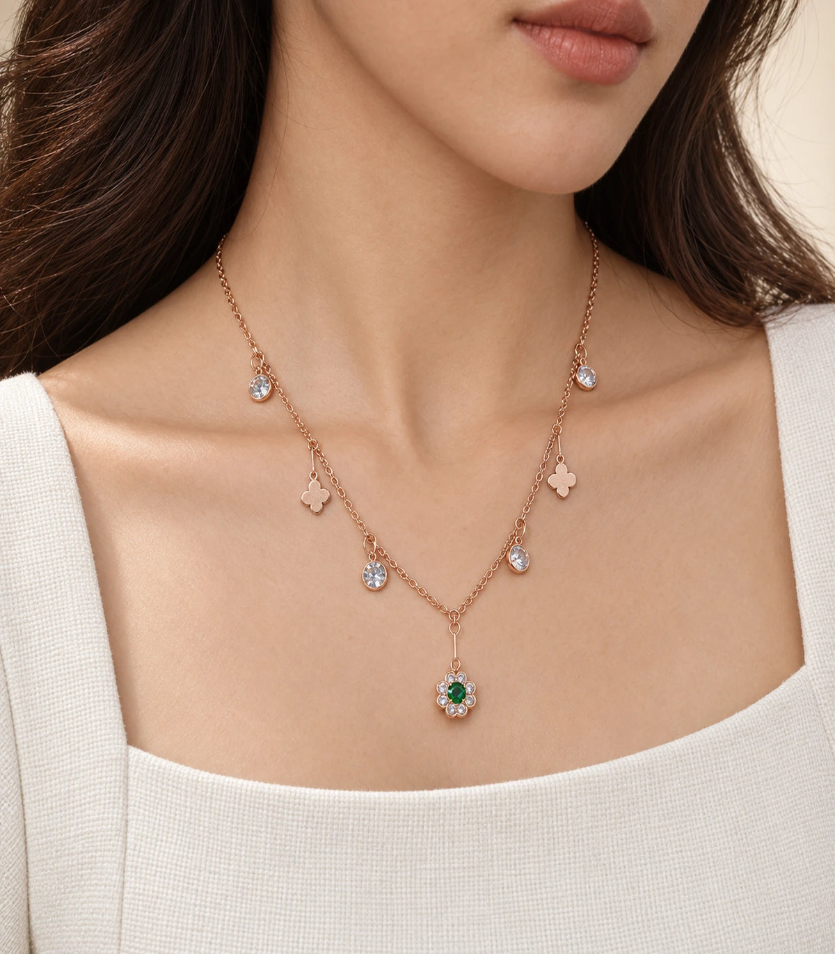 JIMIKI Rose Gold green flower and clover charm necklace, worn in warm light with a cream neckline #color_rose gold