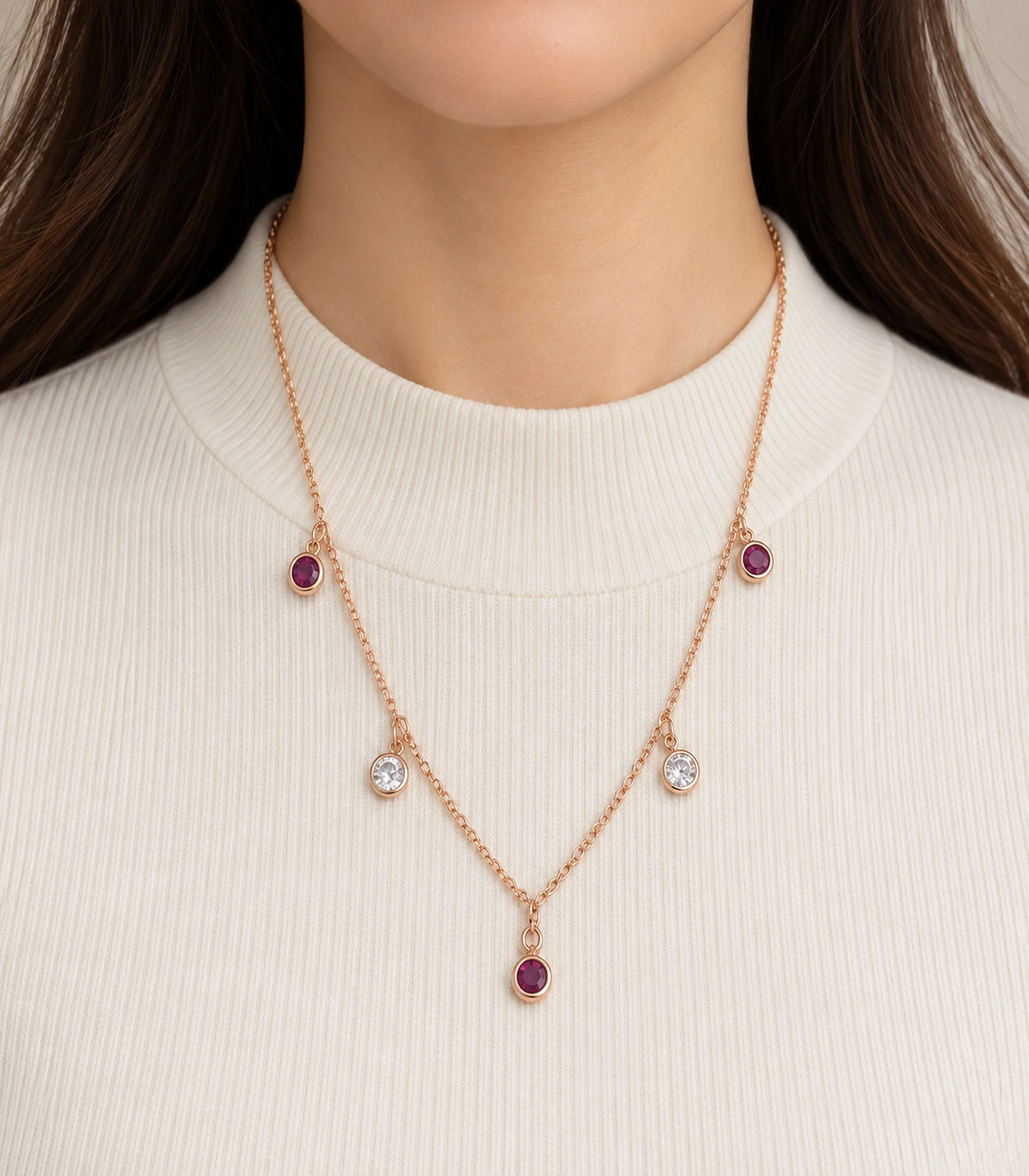 JIMIKI Purple and Clear Five-Stone Station Necklace in rose-gold tone, necklace worn over a cream knit top #color_purple & clear