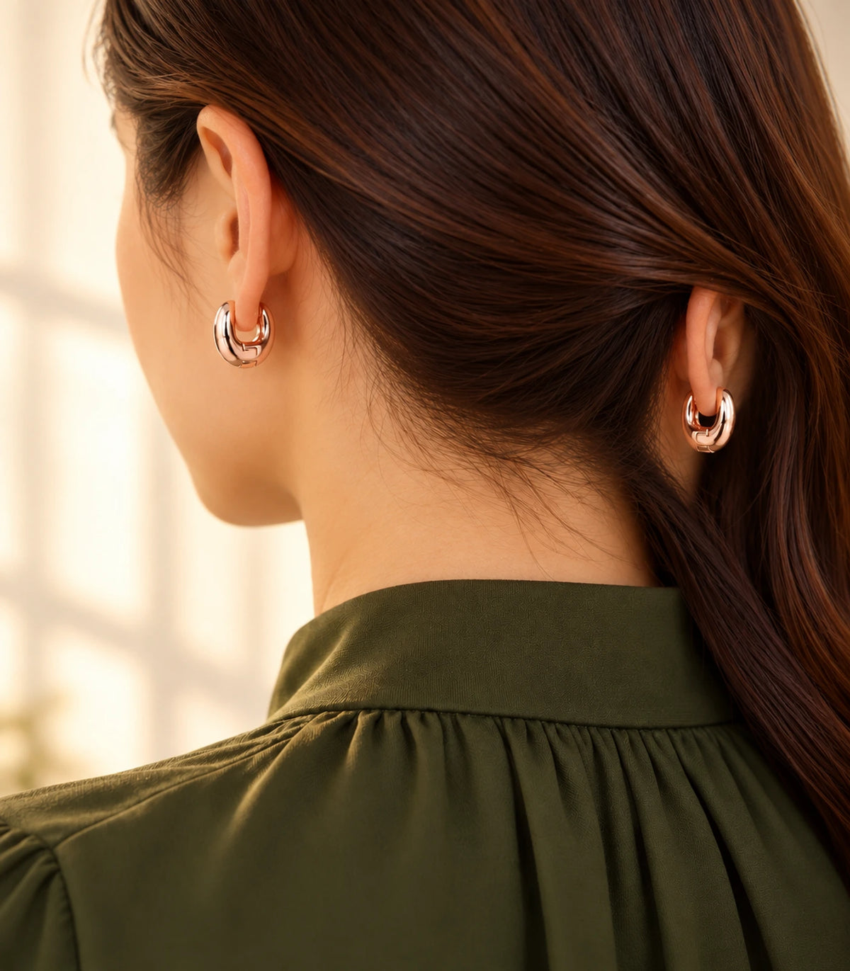 Rose-gold-tone smooth chunky hoop earrings in an editorial worn view.