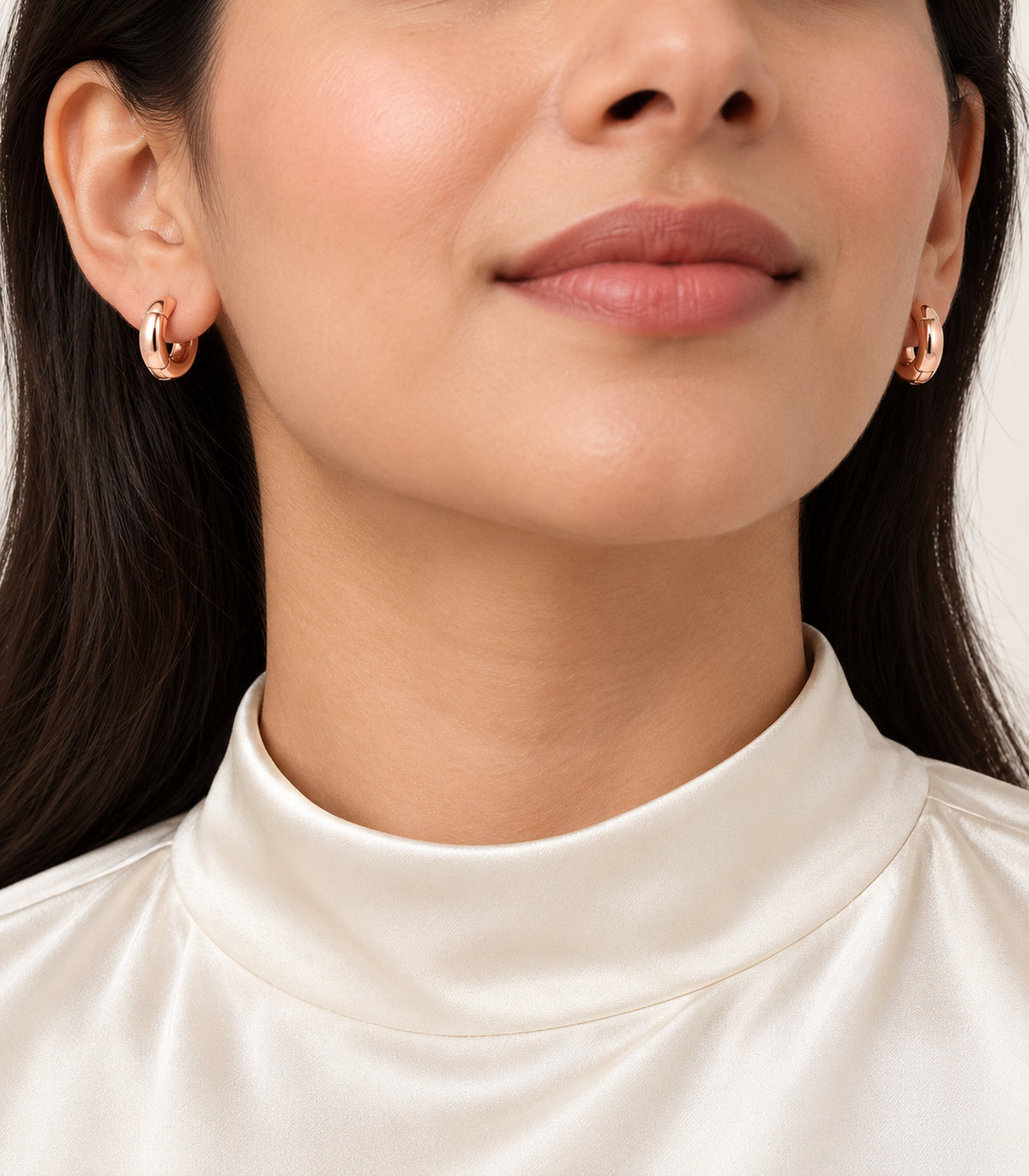 Rose-gold-tone smooth chunky hoop earrings worn by a model.