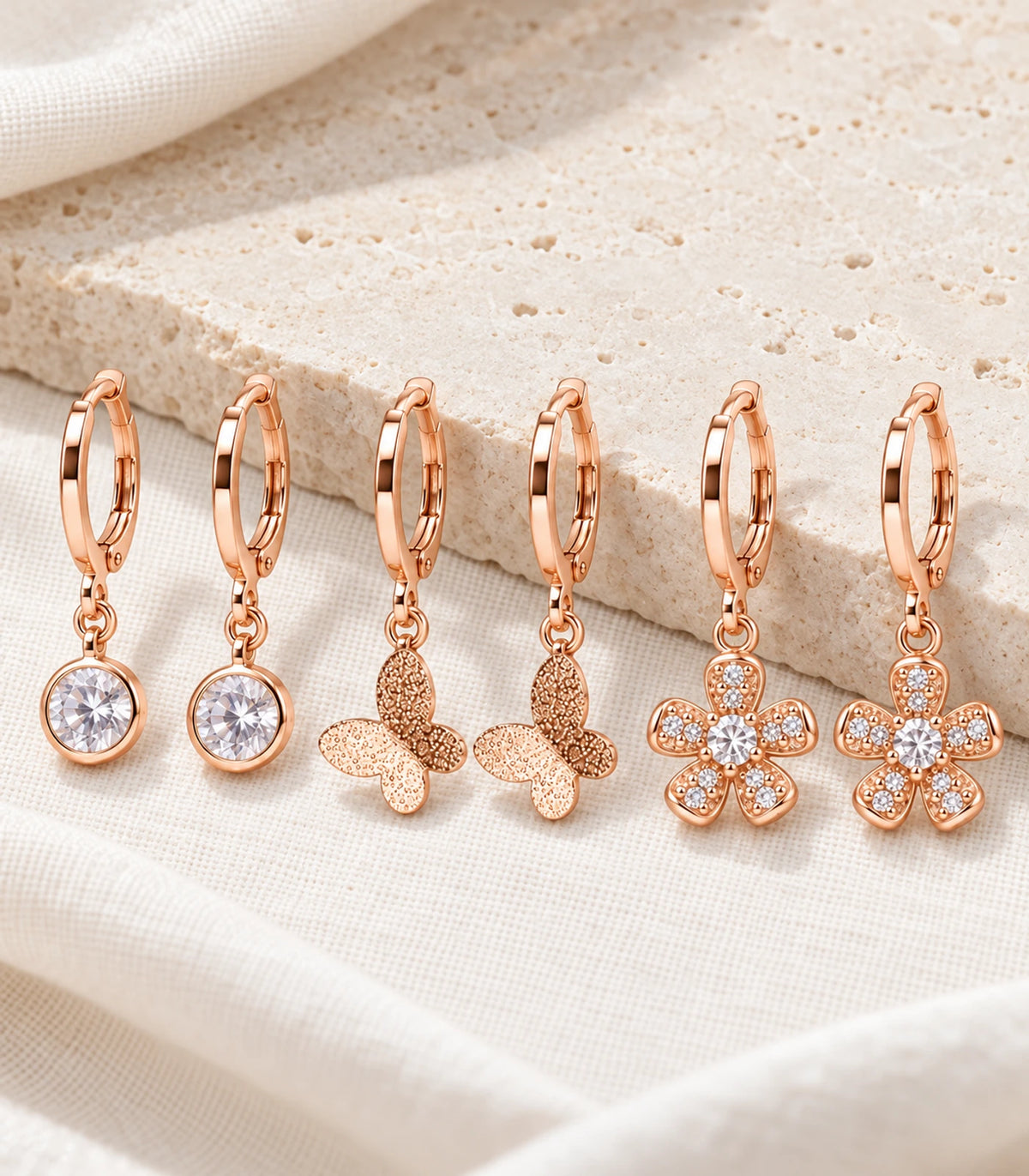 Complete six-earring rose gold tone set with round crystal, butterfly and flower pairs on stone and linen