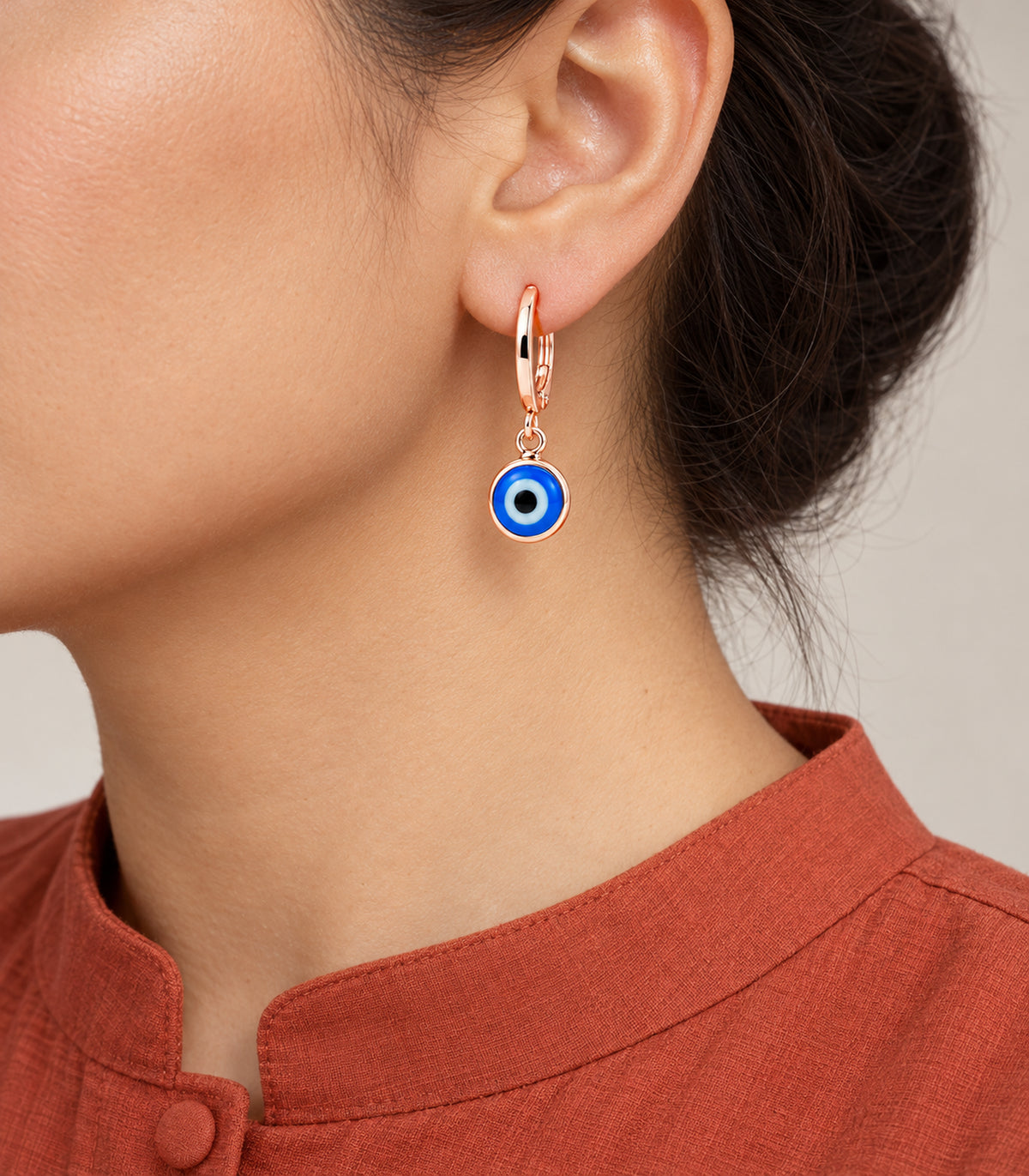 Blue evil-eye charm hoop from the rose gold tone three-pair set worn on one ear