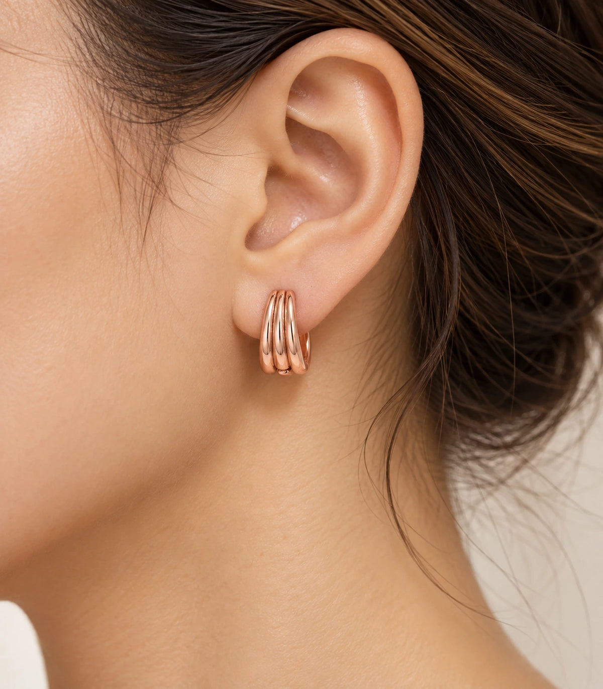 JIMIKI Triple-Ridge Huggie Hoop Earrings in Rose Gold Tone - editorial-model #color_rose-gold-tone