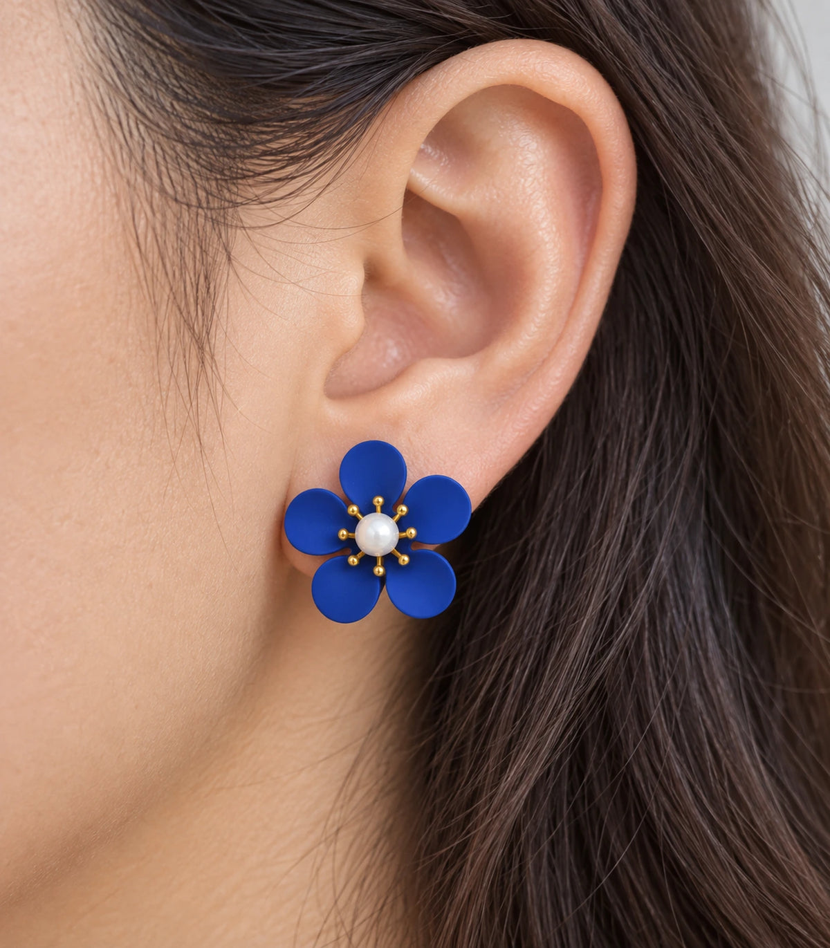 JIMIKI royal blue five-petal flower stud earrings with pearl-effect centre, closeup of flower stud in a natural worn setting #color_royal-blue