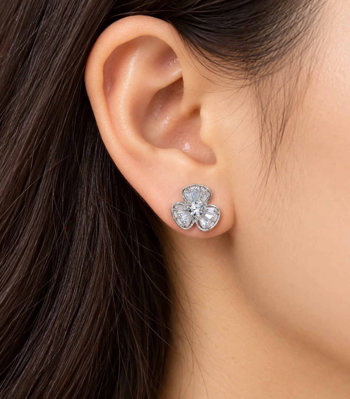 Silver-tone three-petal flower stud earring worn on an ear