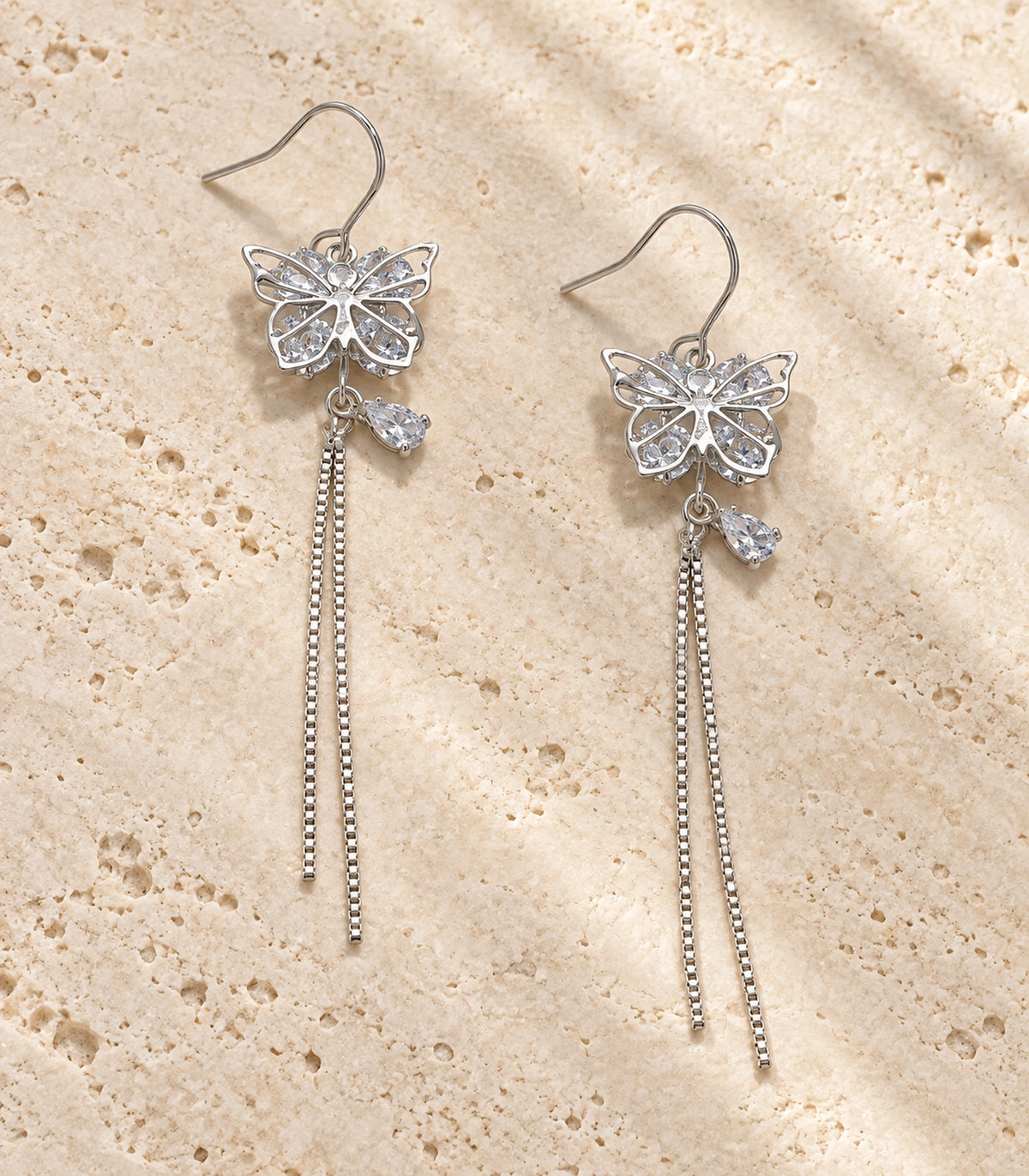 JIMIKI Silver Butterfly Crystal Chain Drop Earrings in Silver Tone, editorial flat lay