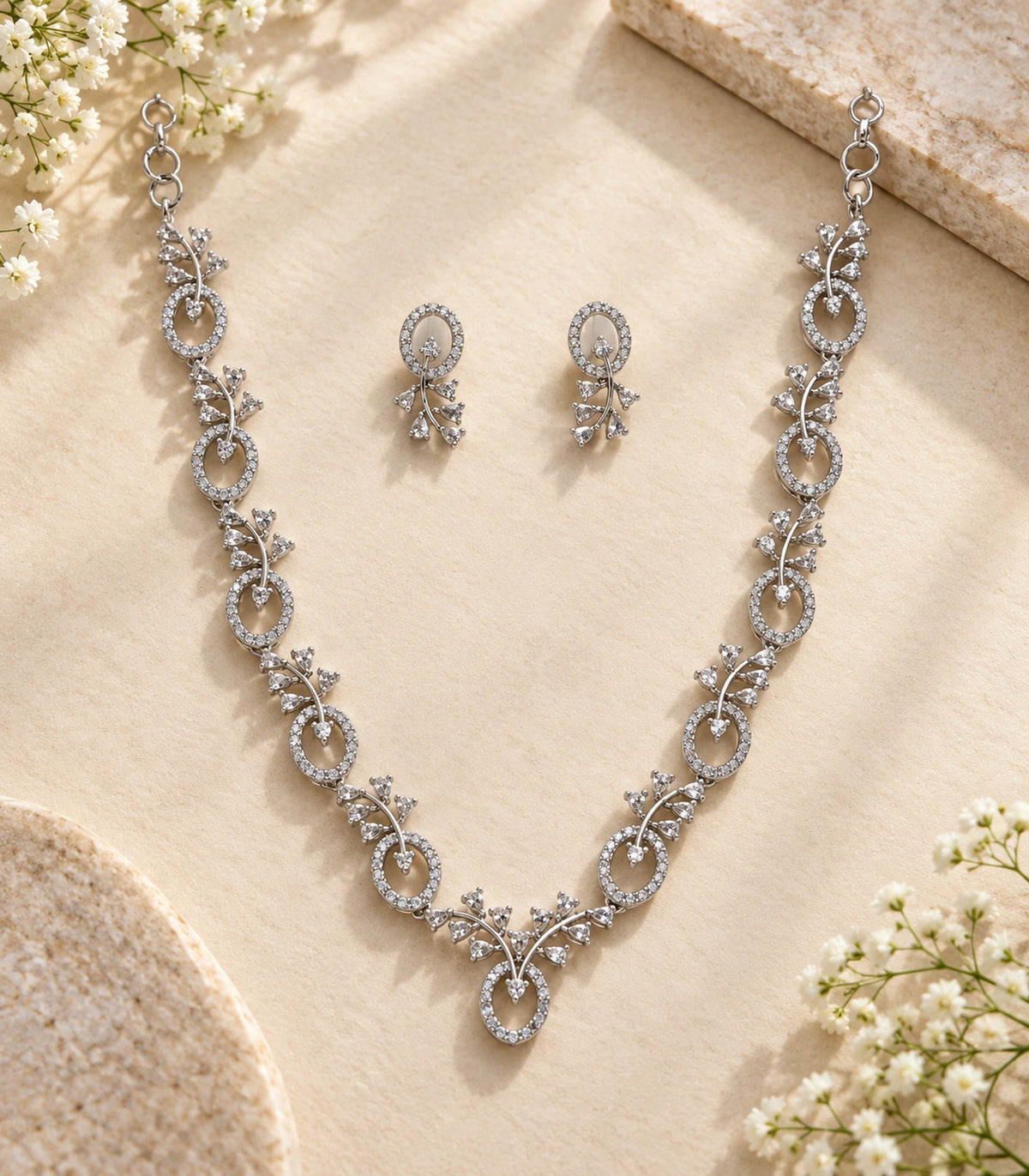 Silver Clear Floral Drop Crystal Necklace Set with matching earrings arranged on a cream surface