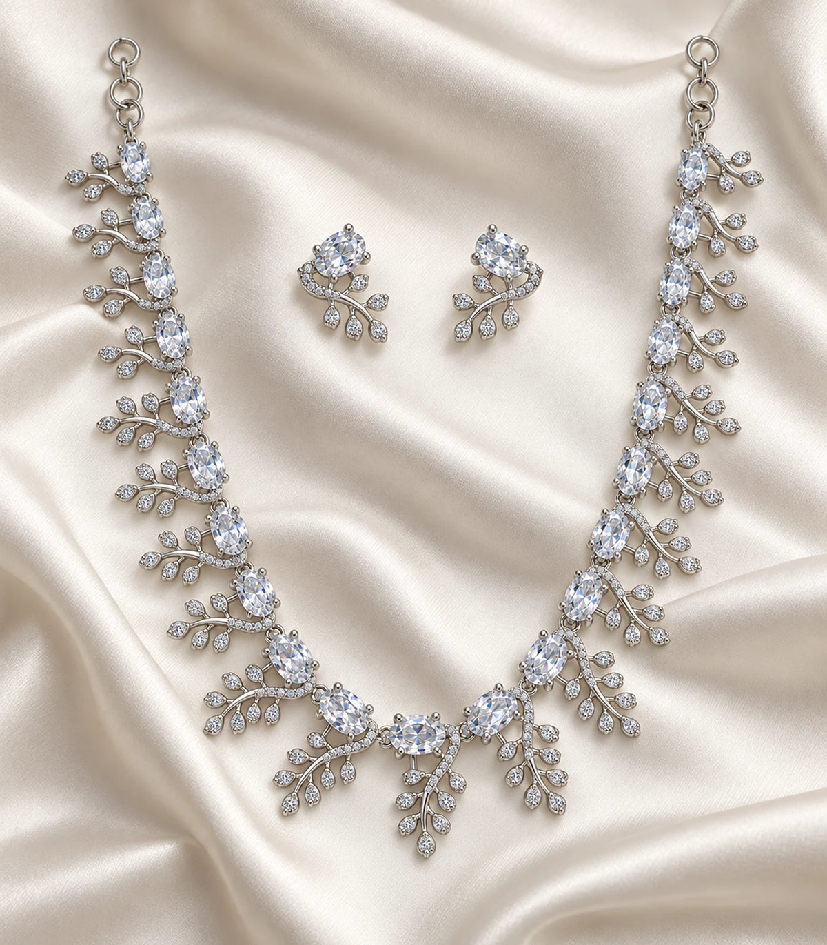 Complete silver-tone clear leaf-cluster necklace set arranged on ivory fabric