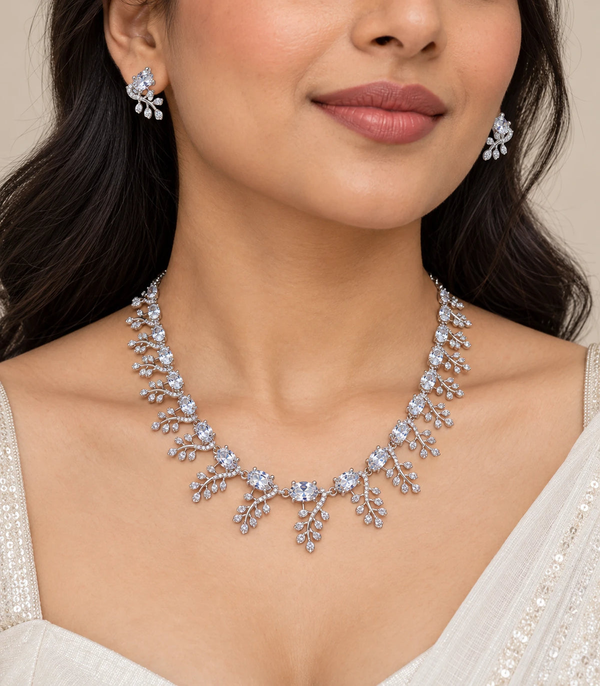 Silver-tone clear leaf-cluster necklace and matching earrings worn with an ivory outfit