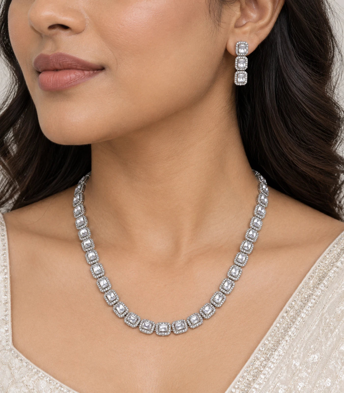 Close worn view of the clear halo necklace and matching three-section earring