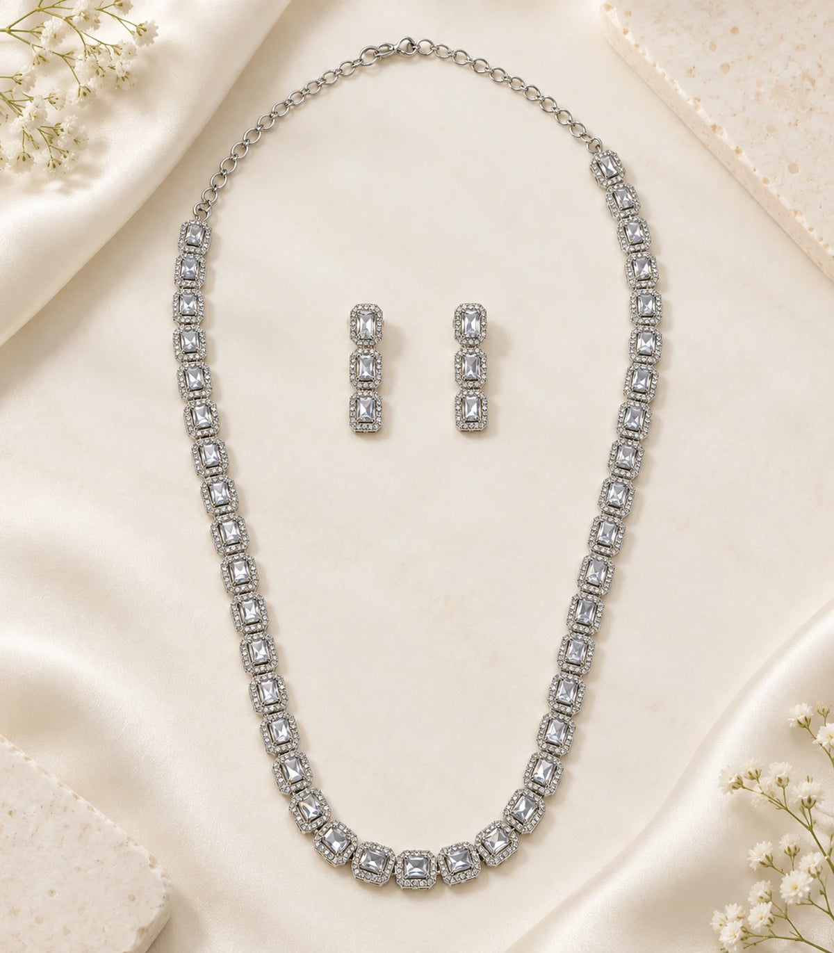 Complete clear halo necklace and matching earring pair arranged on cream fabric