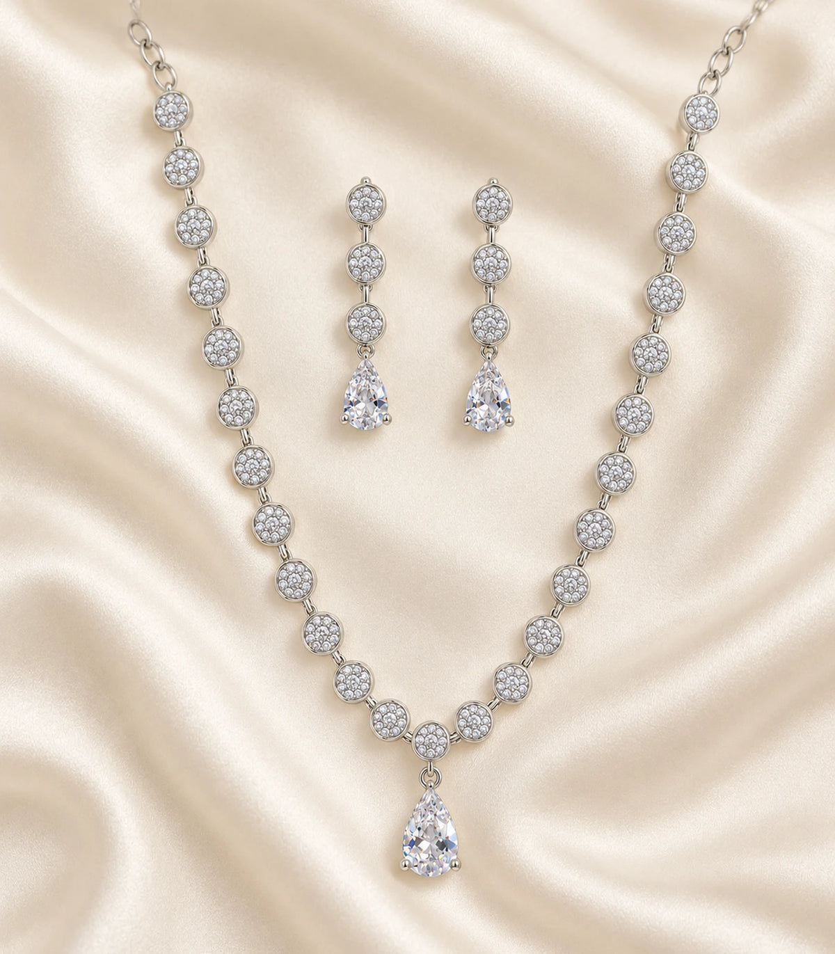 Silver clear round crystal drop necklace set with matching earrings arranged on fabric