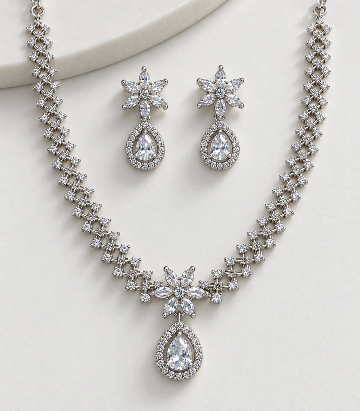 Detail of silver clear floral motifs and teardrop accents on necklace and matching earrings